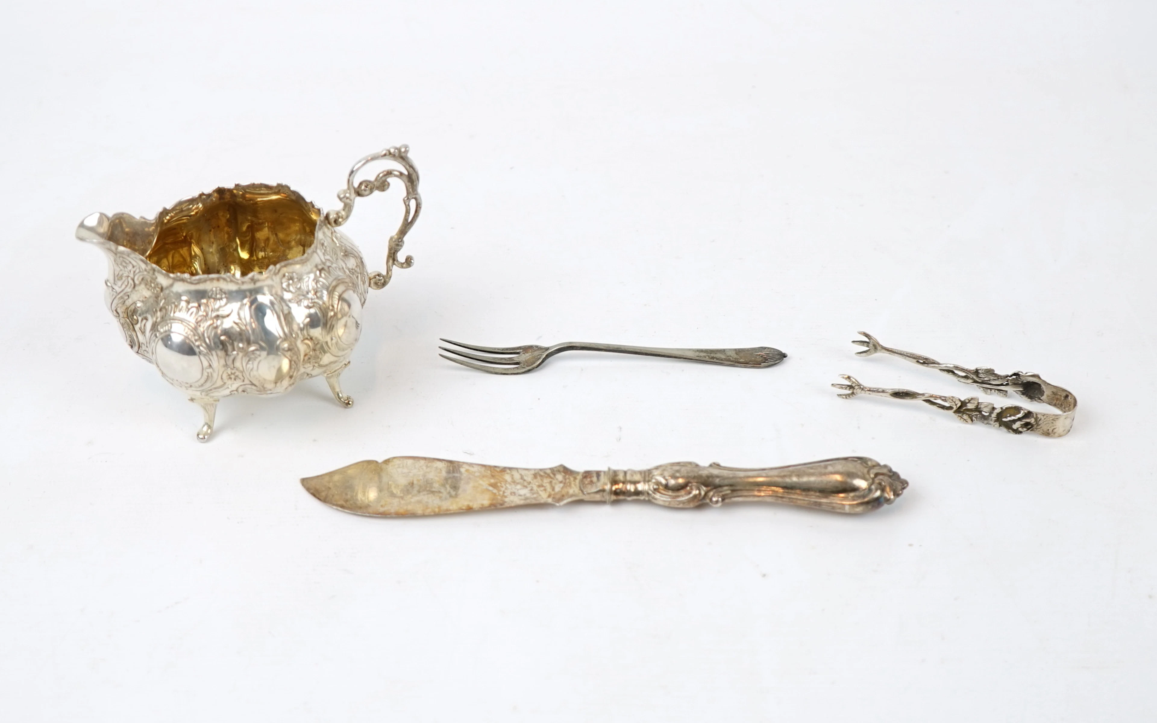Jarra de crema, tenedor, tenazas y cuchillo, de plata.