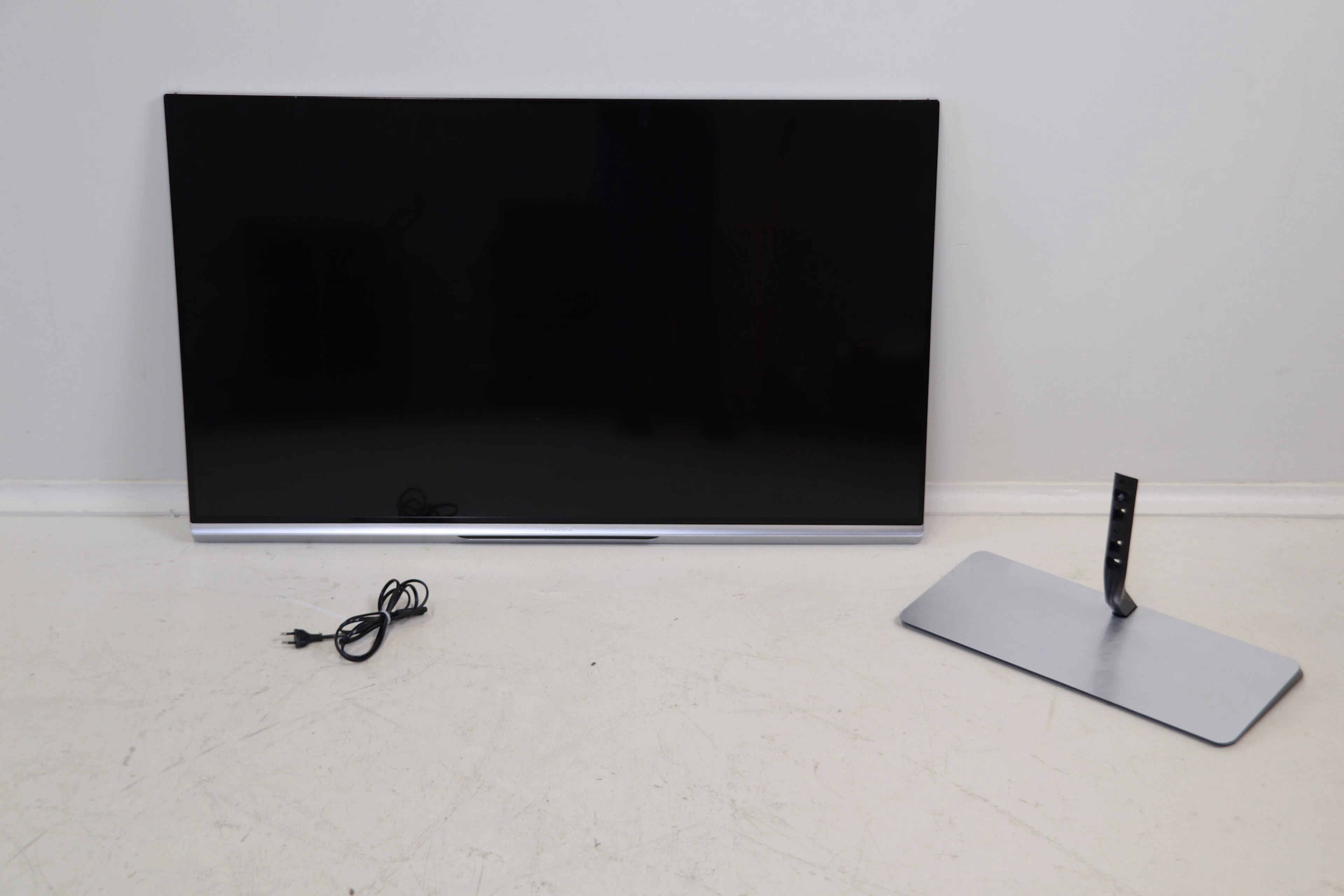 Smart TV, Philips 47PFL6877T/12, ainsi qu’un meuble TV et un câble.