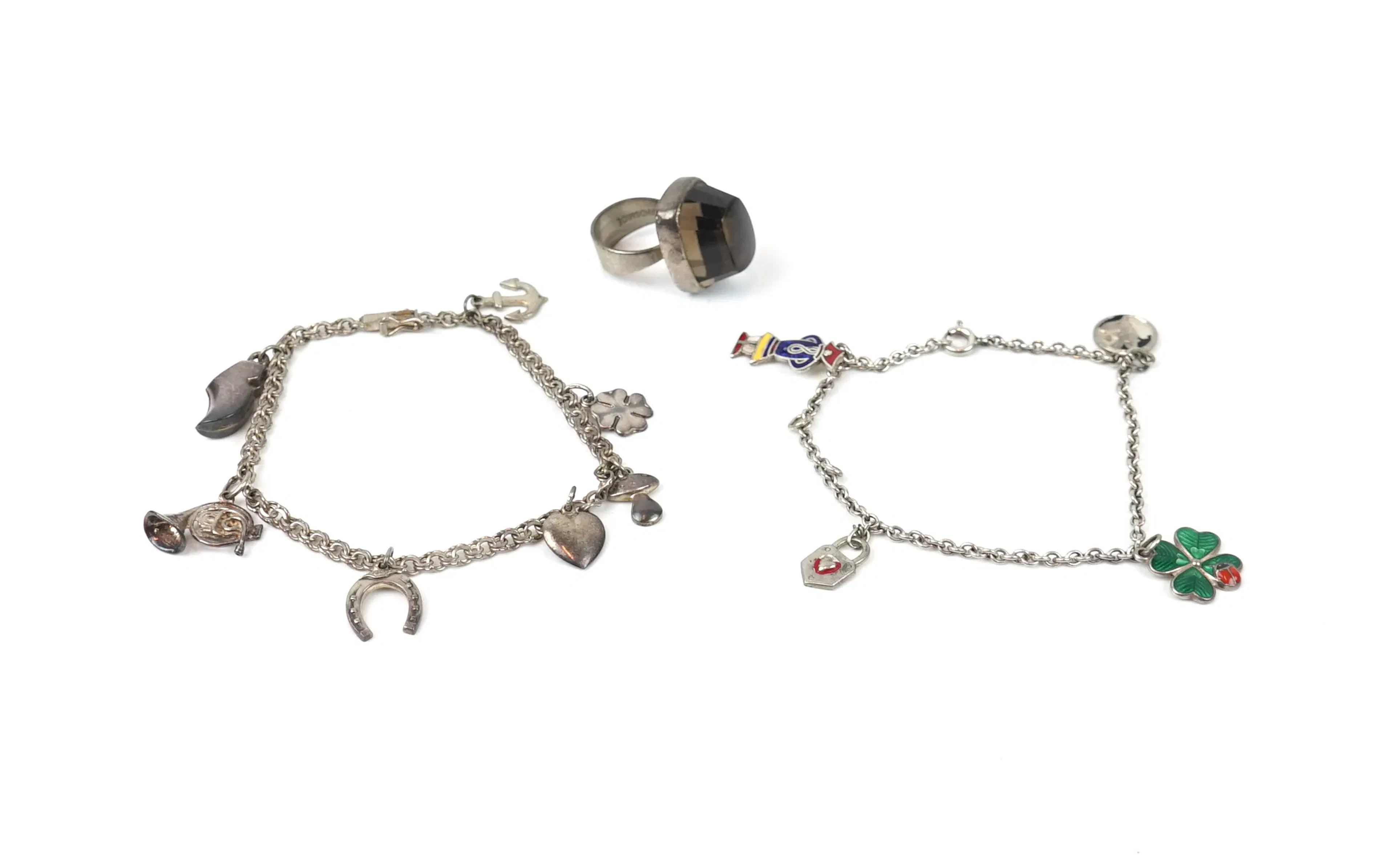 Pulseras, 2 con amuletos y un anillo con piedra color humo, plateada.