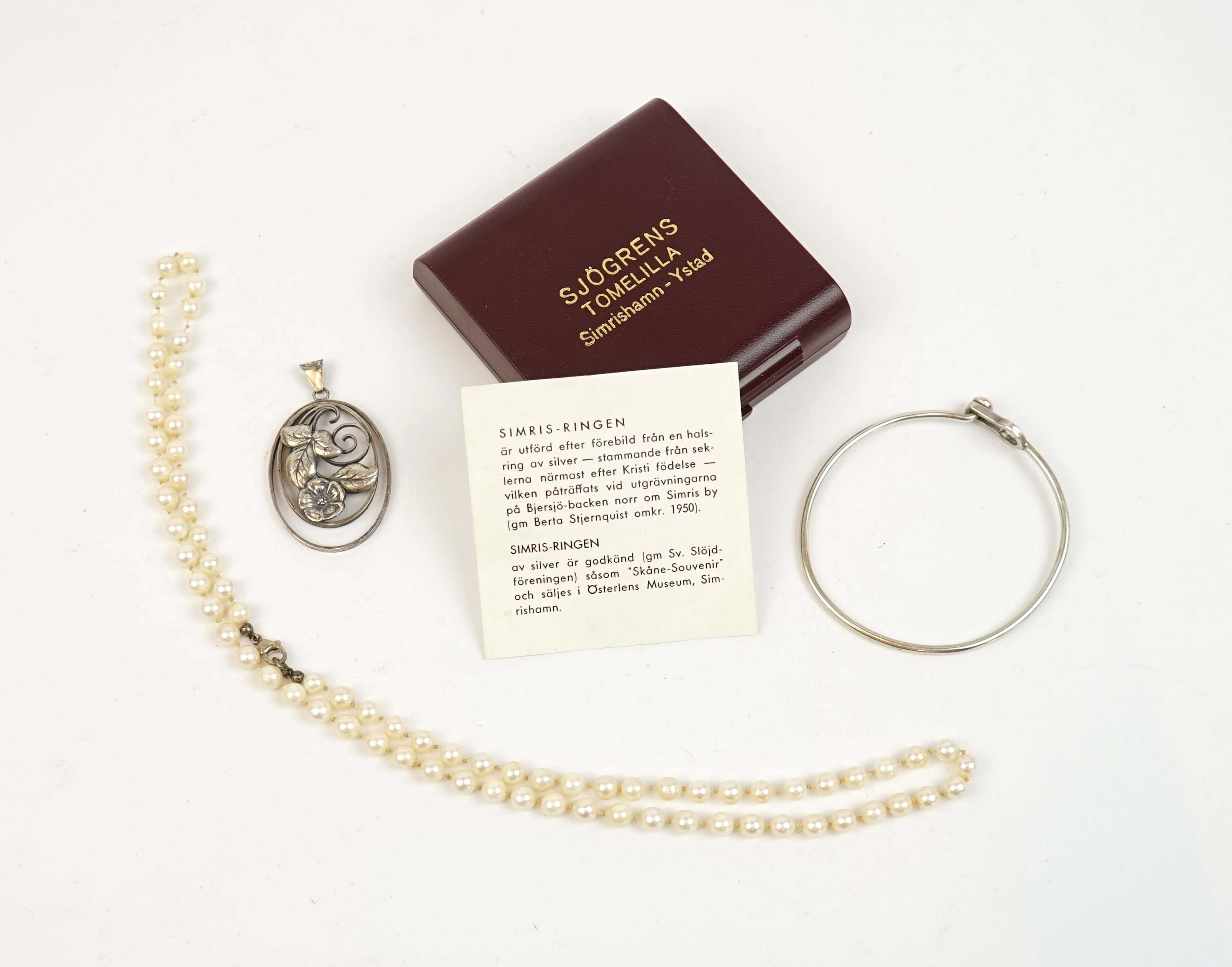 Collana di perle con chiusura in argento, oltre a un bracciale rigido e pendente in argento.