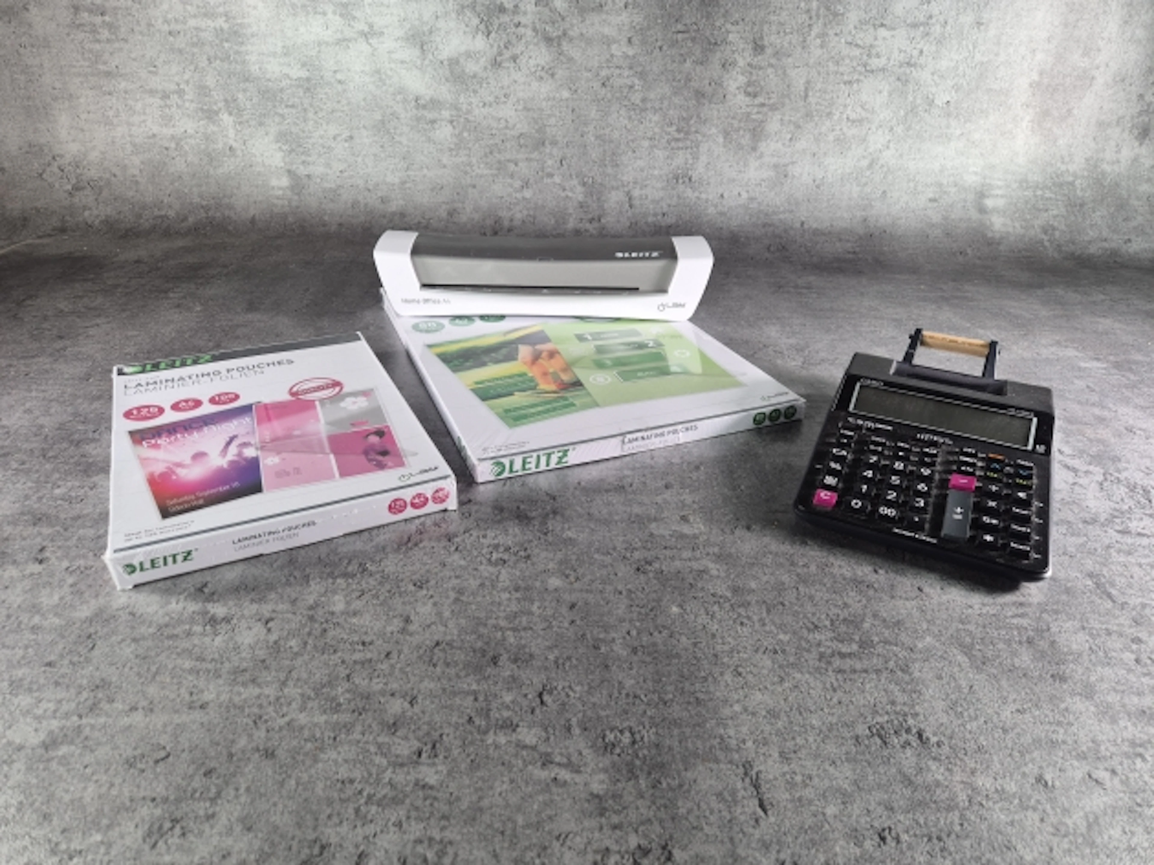 Laminator, miniräknare och papper.