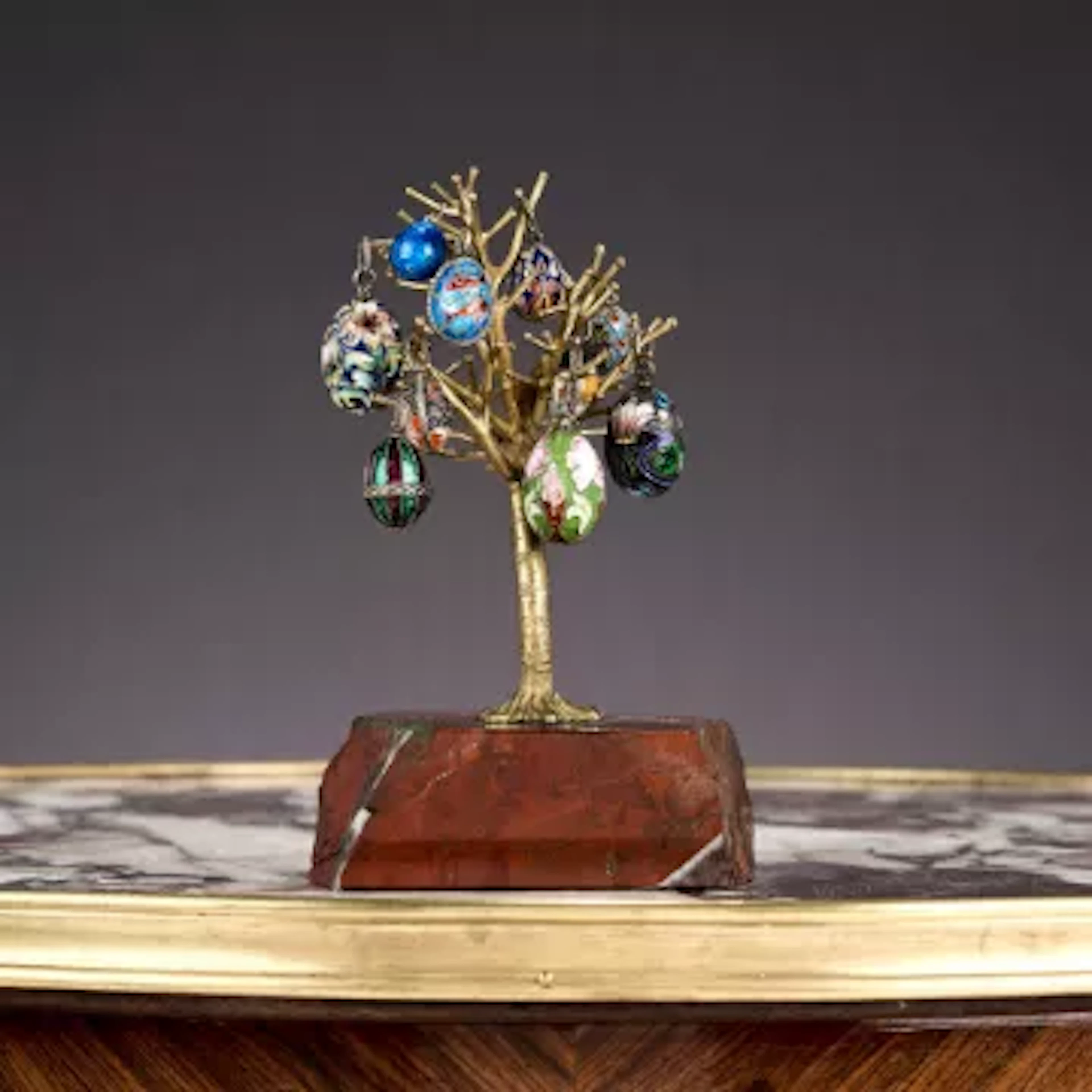 TEN RUSSIAN CLOISONNE ENAMEL AND SILVER EGG PENDANTS MOUNTED ON A STAND