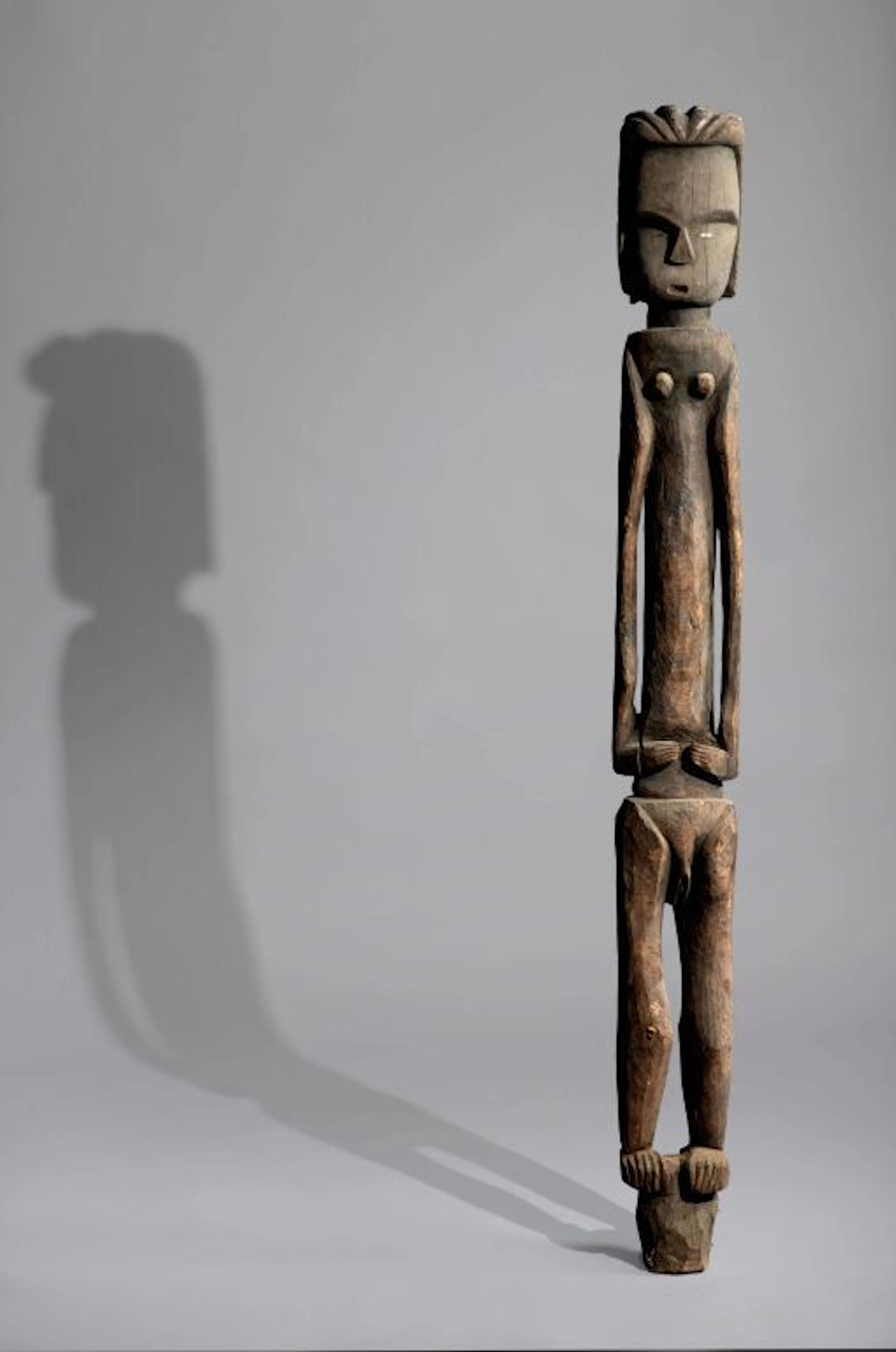 A female sculpture standing on a pedestal or a fragment of a post.