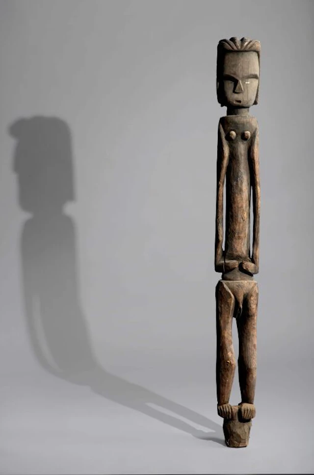 A female sculpture standing on a pedestal or a fragment of a post.