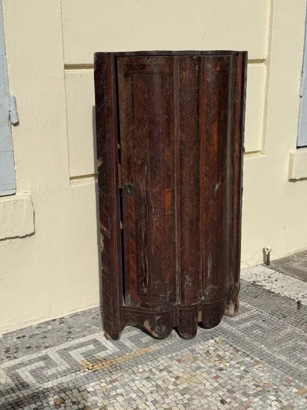 A charming corner cabinet made of inlaid wood, featuring a dynamic