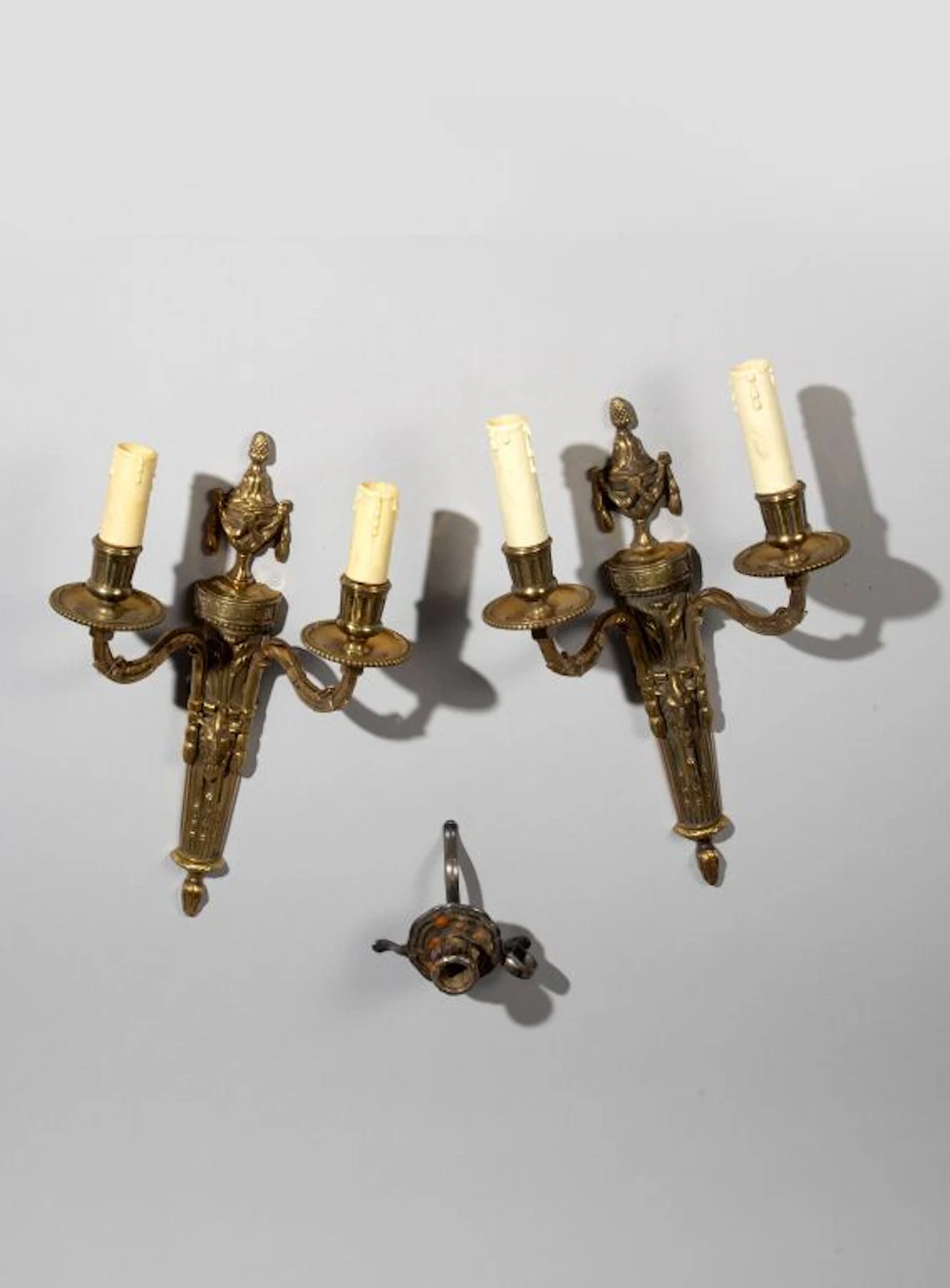 A pair of Louis XVI-style two-arm wall sconces made of varnished bronze