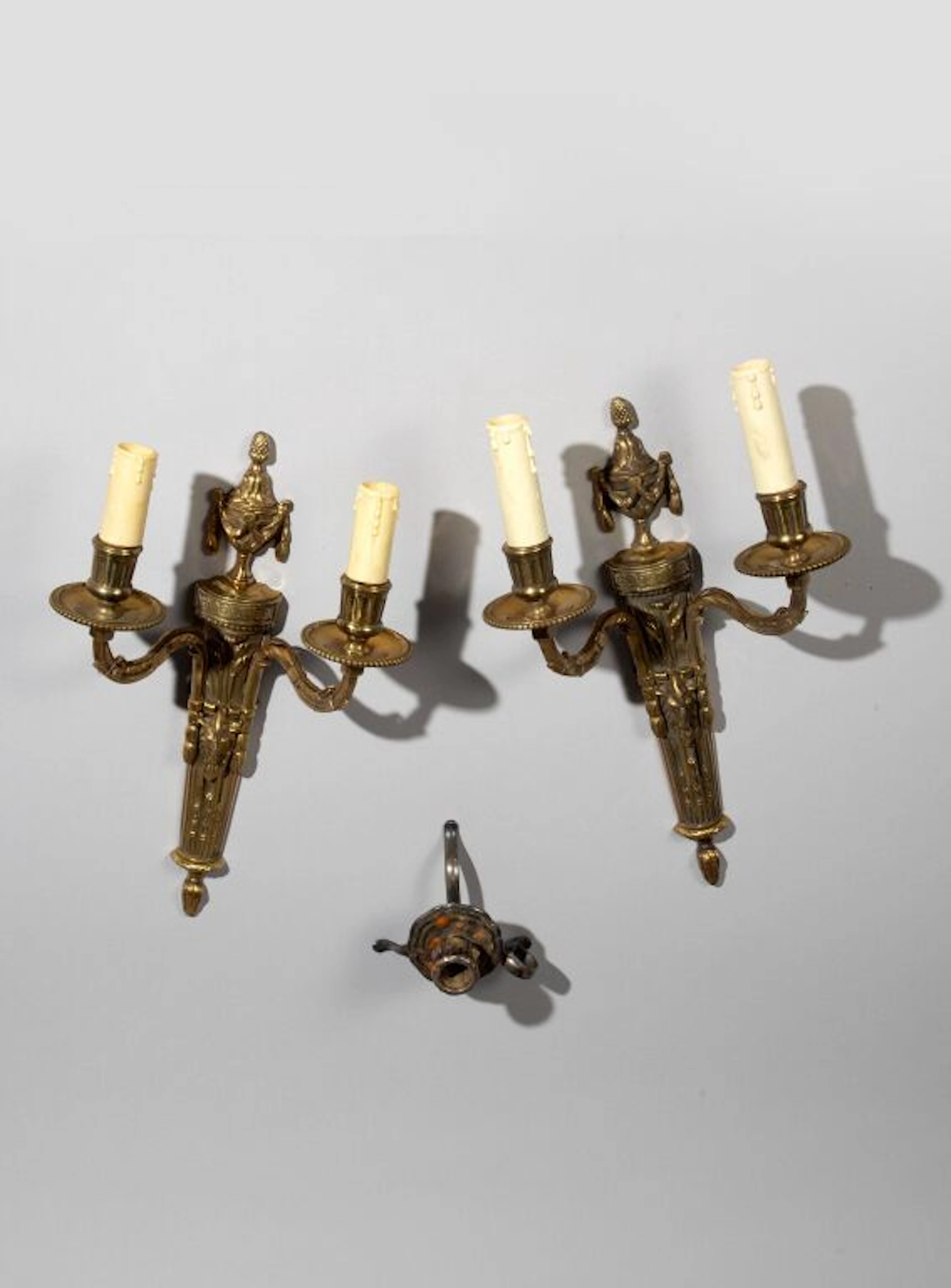 A pair of Louis XVI-style two-arm wall sconces made of varnished bronze