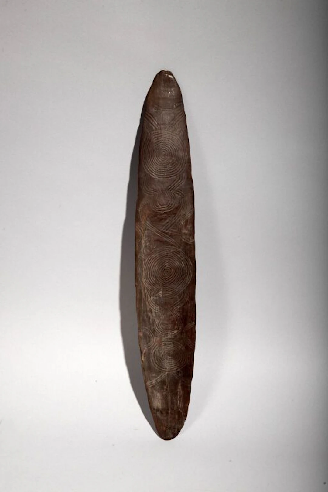 Churinga votive palette engraved with circular motifs on both sides.