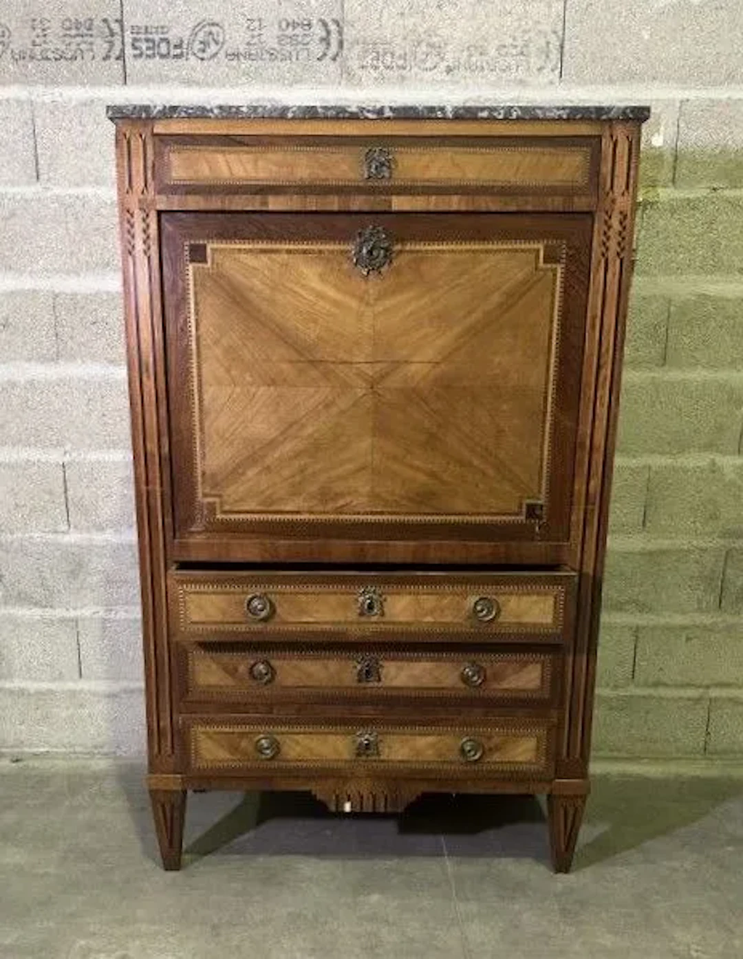 A veneered wooden secretary desk with a marquetry design featuring