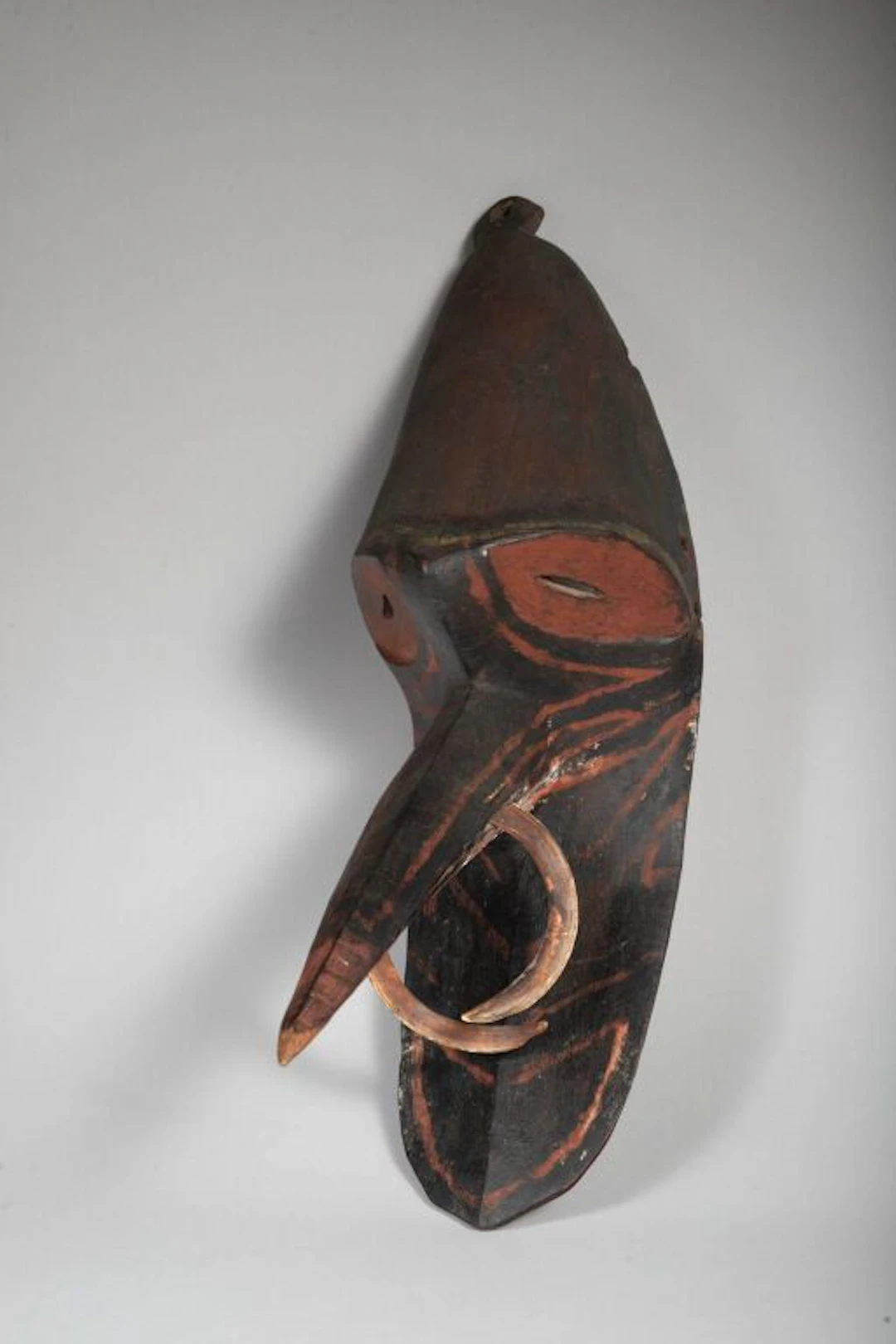 Mosquito mask with eyes painted with red pigments. Nasal ornament