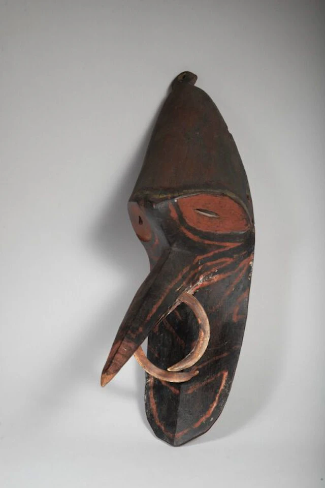 Mosquito mask with eyes painted with red pigments. Nasal ornament