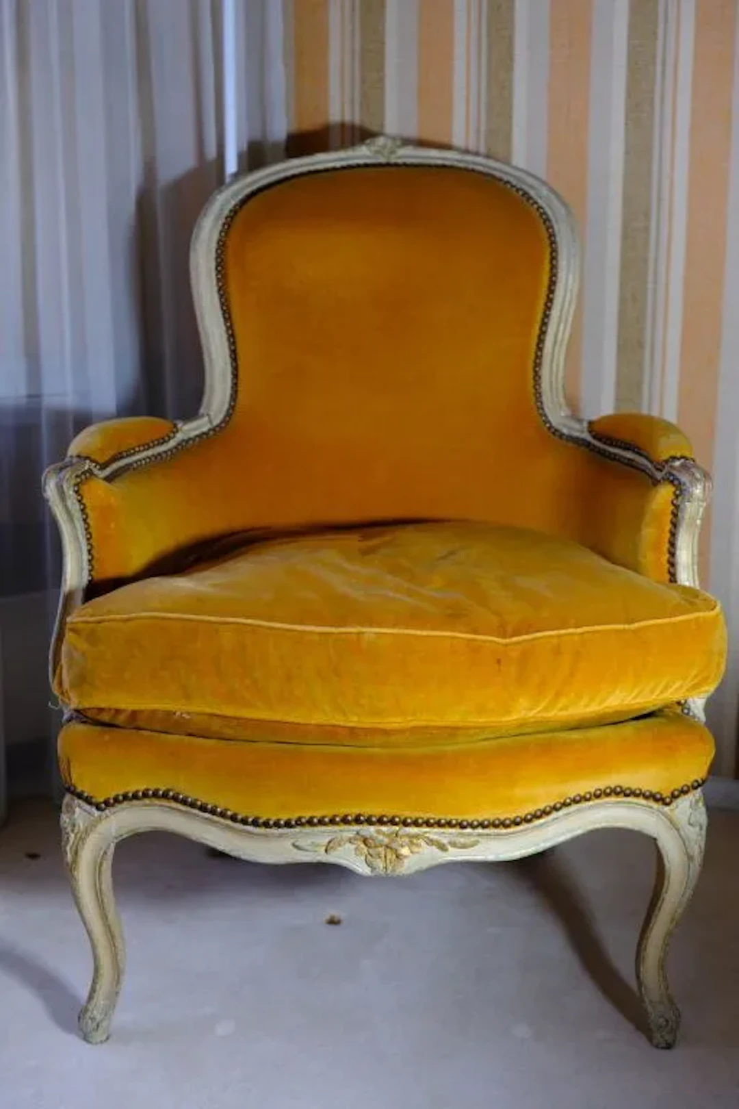 Bergère chair with a curved backrest made of cream-stained wood accented