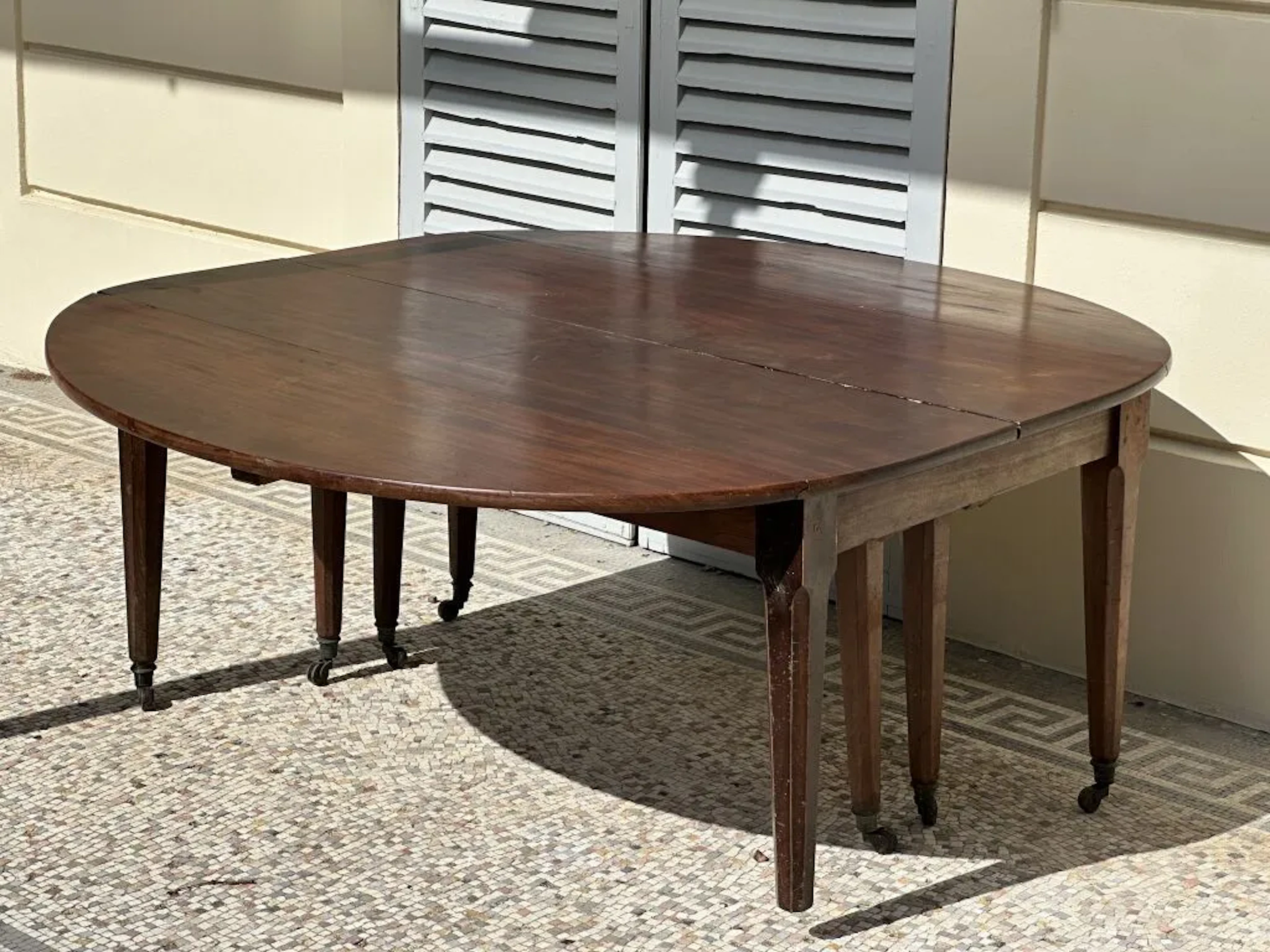 Mahogany dining table with a drop-leaf top on faceted column legs.