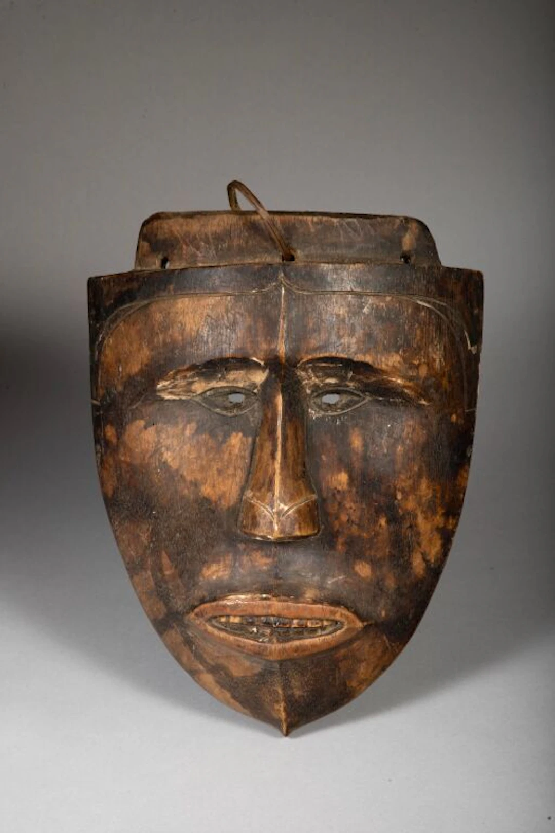 A shield-shaped mask that still bears traces of its original polychrome