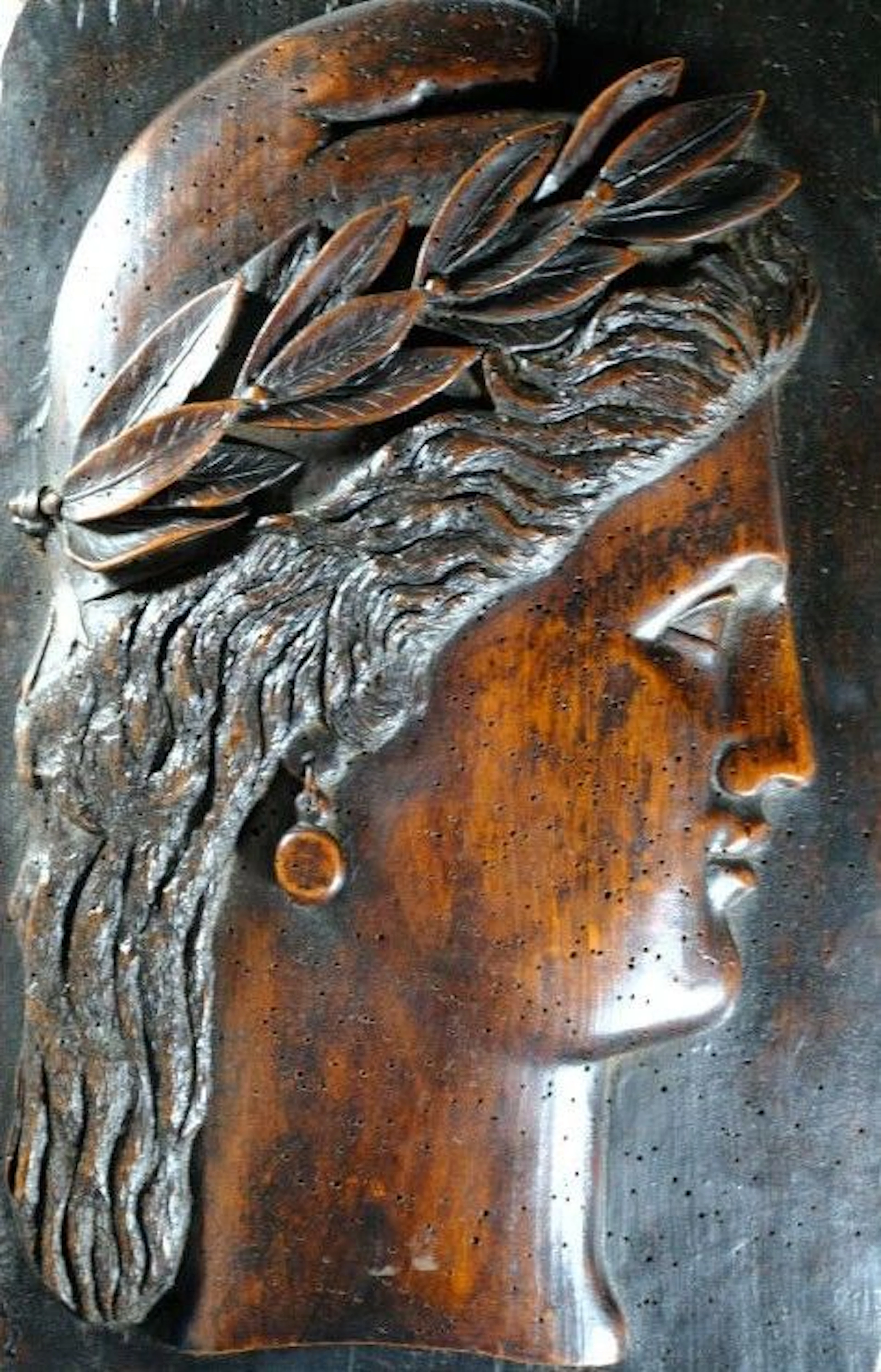 A carved wooden profile of Marianne, wearing a Phrygian cap and a