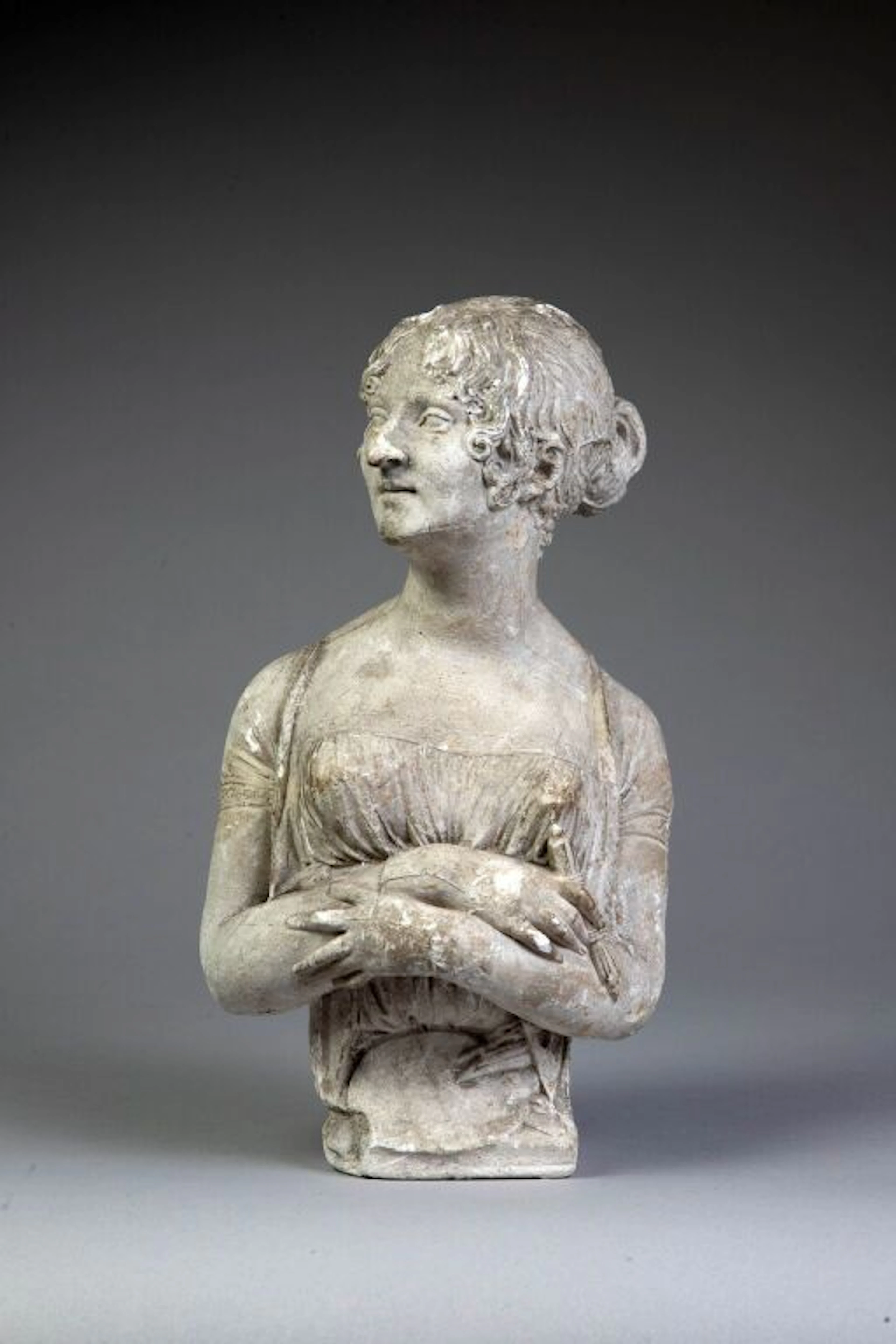 Bust portrait of a woman with her hair in a bun. Cast plaster. Signed