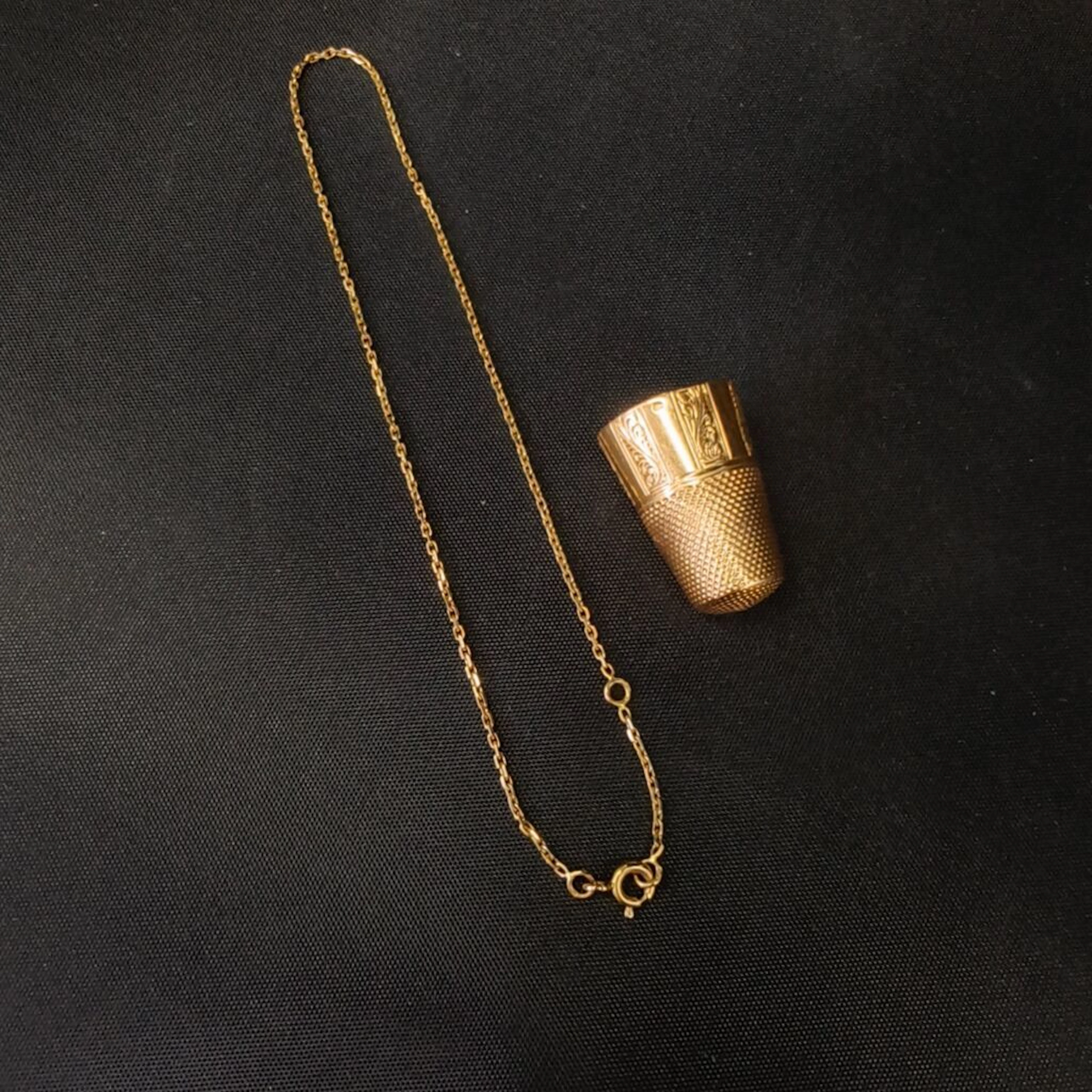 750‰ gold set including: - A thimble engraved with plant motifs, NET