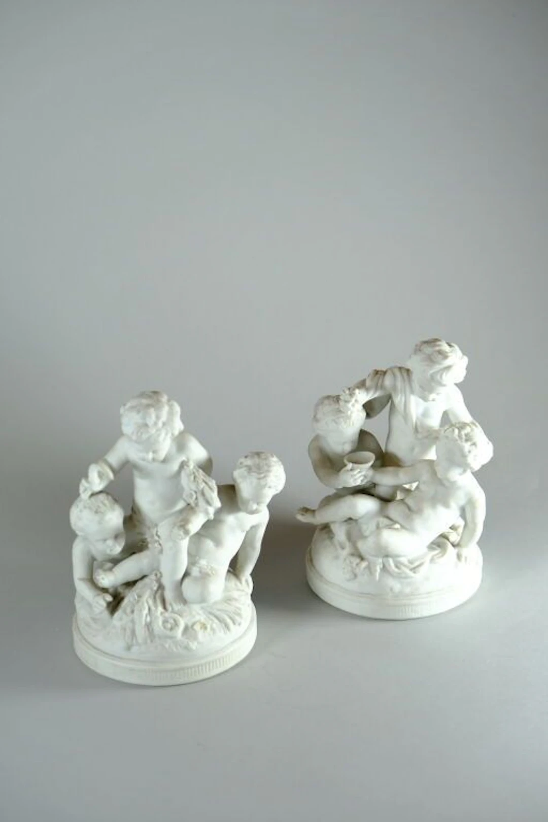 SEVRES, France. Two sculpted groups of putti in bisque porcelain depicting