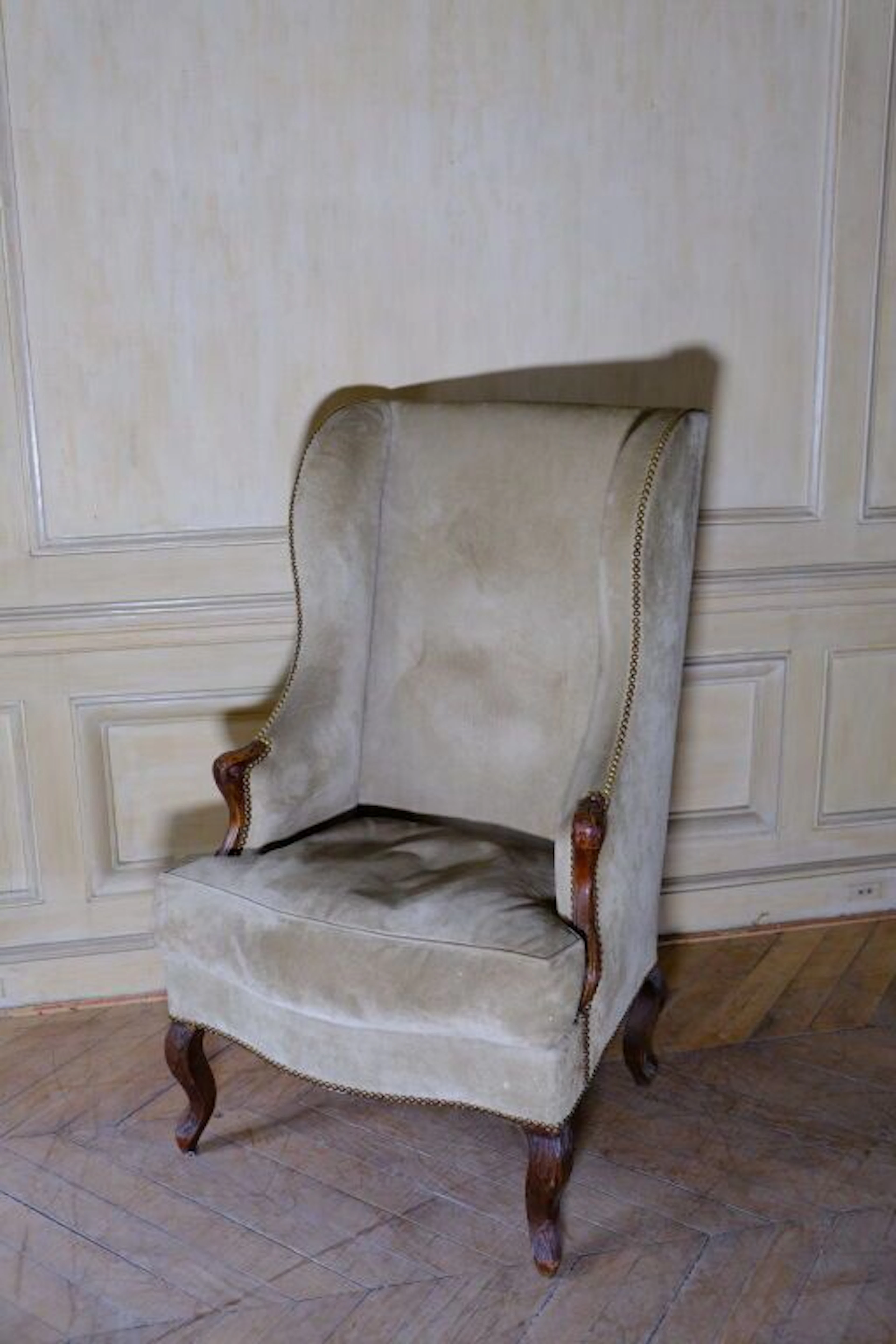 Carved wooden wingback chair with foliage decoration, whip-curved