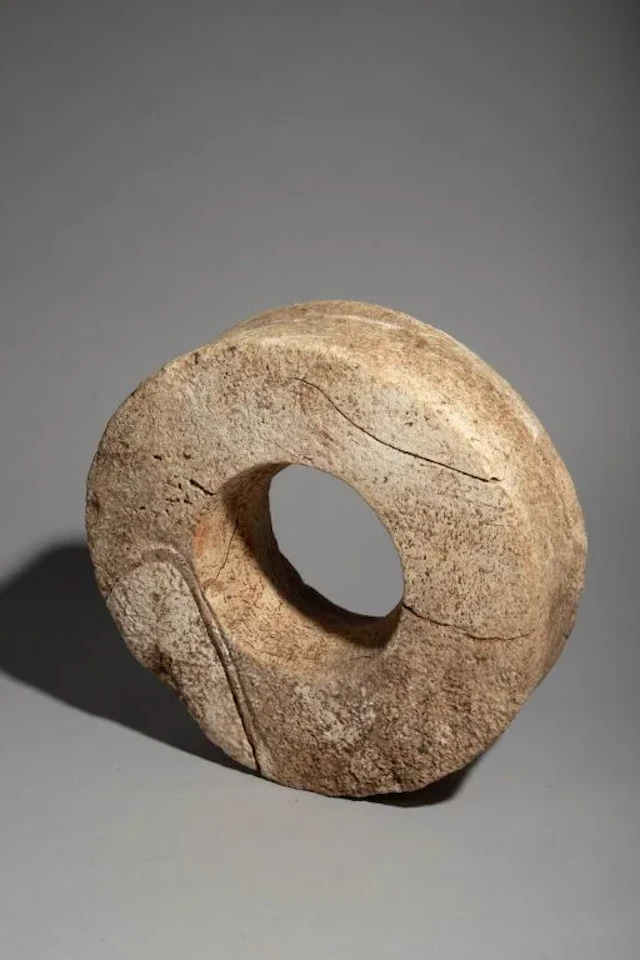 Circular traditional currency made from a white fossilized seashell.