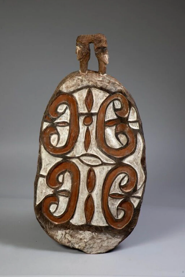 An Asmat votive plaque carved from wood, elongated in shape, featuring