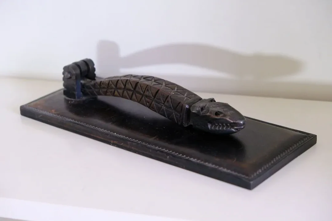 A paperweight shaped like a door knocker, featuring a removable wrought-iron