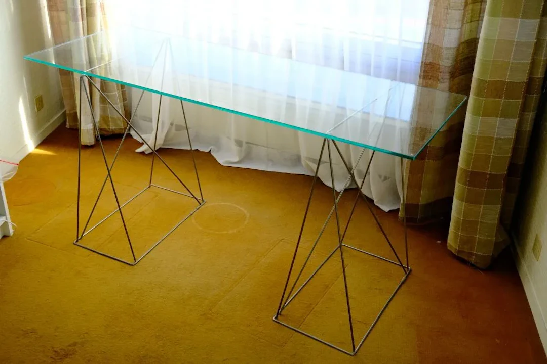 A modernist console table featuring a rectangular glass top resting