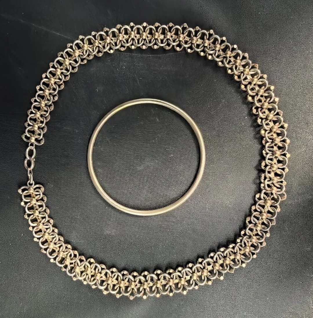 800‰ silver set including: - A bangle. Diameter: 6 cm; - An interlaced-link