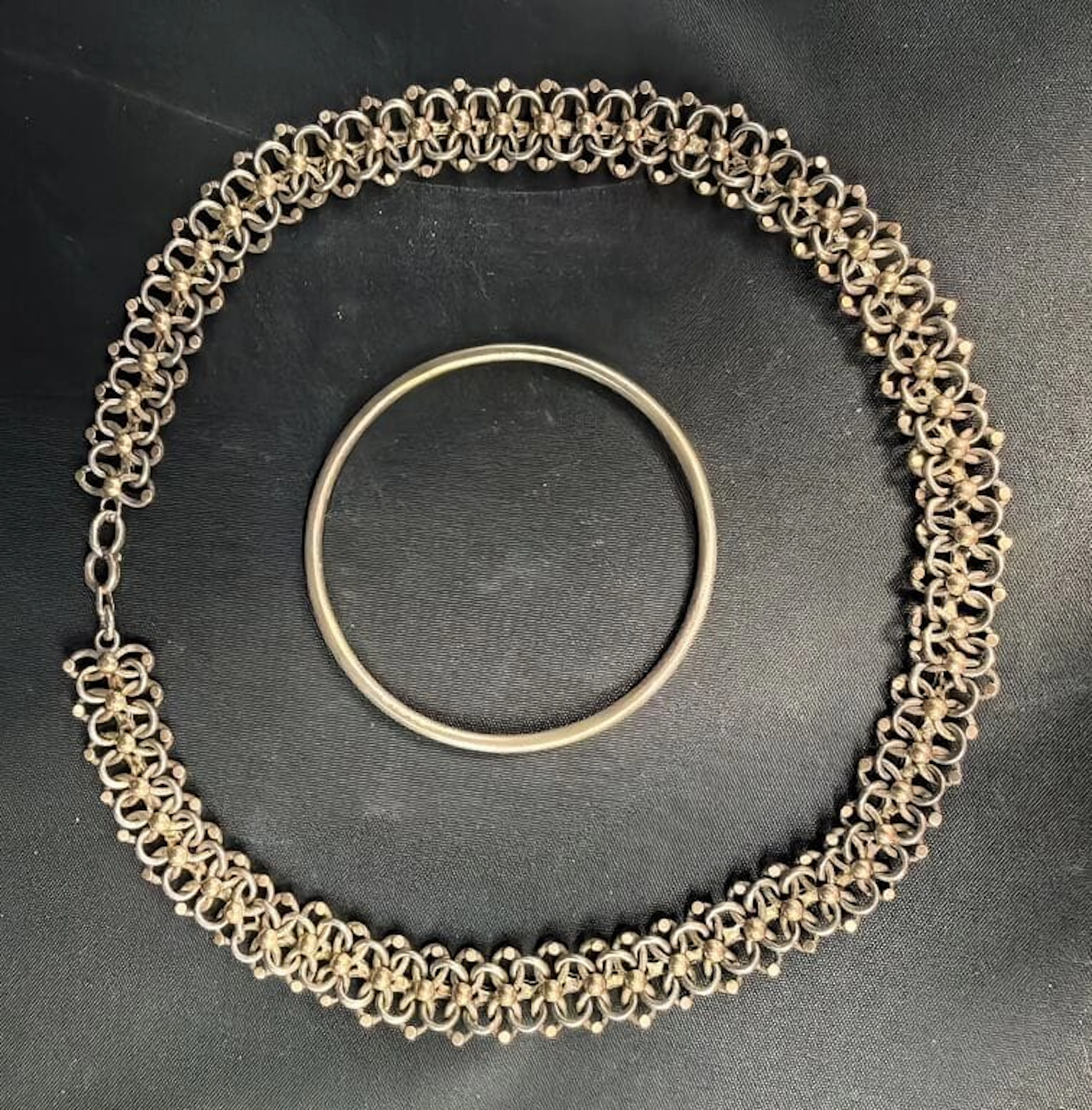 800‰ silver set including: - A bangle. Diameter: 6 cm; - An interlaced-link