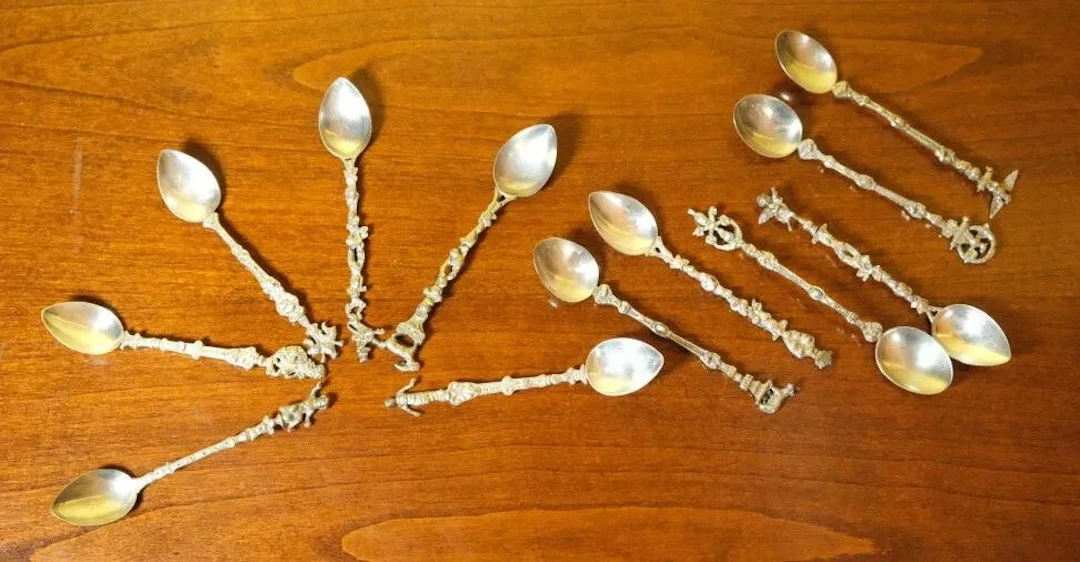 A set of 12 small silver-plated coffee spoons, each featuring a rounded