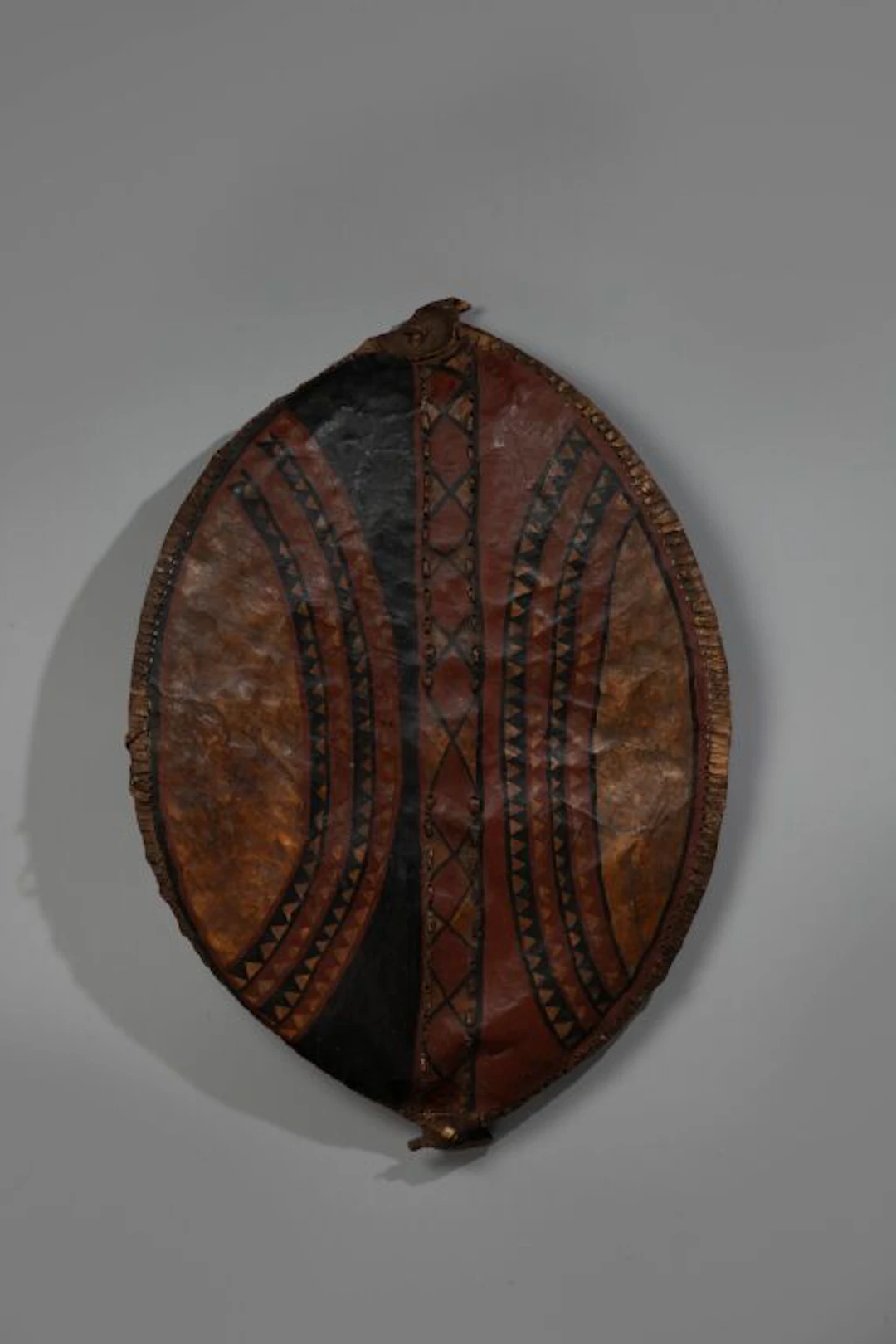 Almond-shaped shield. Leather stretched and sewn over a curved wooden