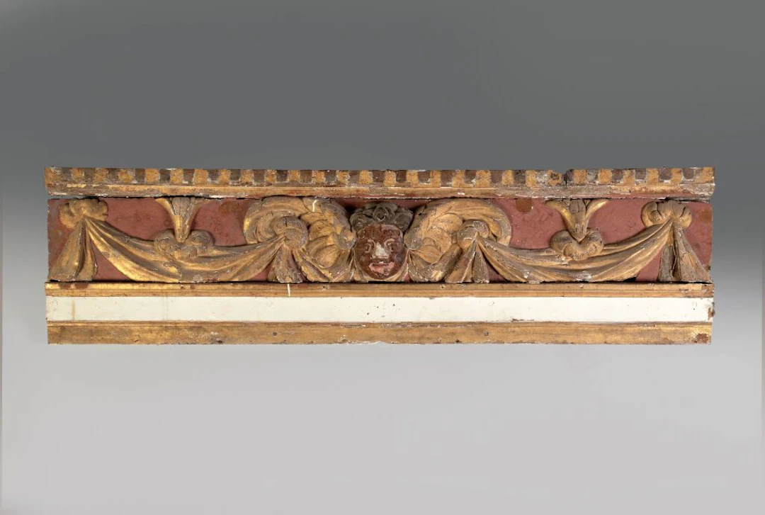 A carved and gilded wood panel, repainted in ochre and white, decorated