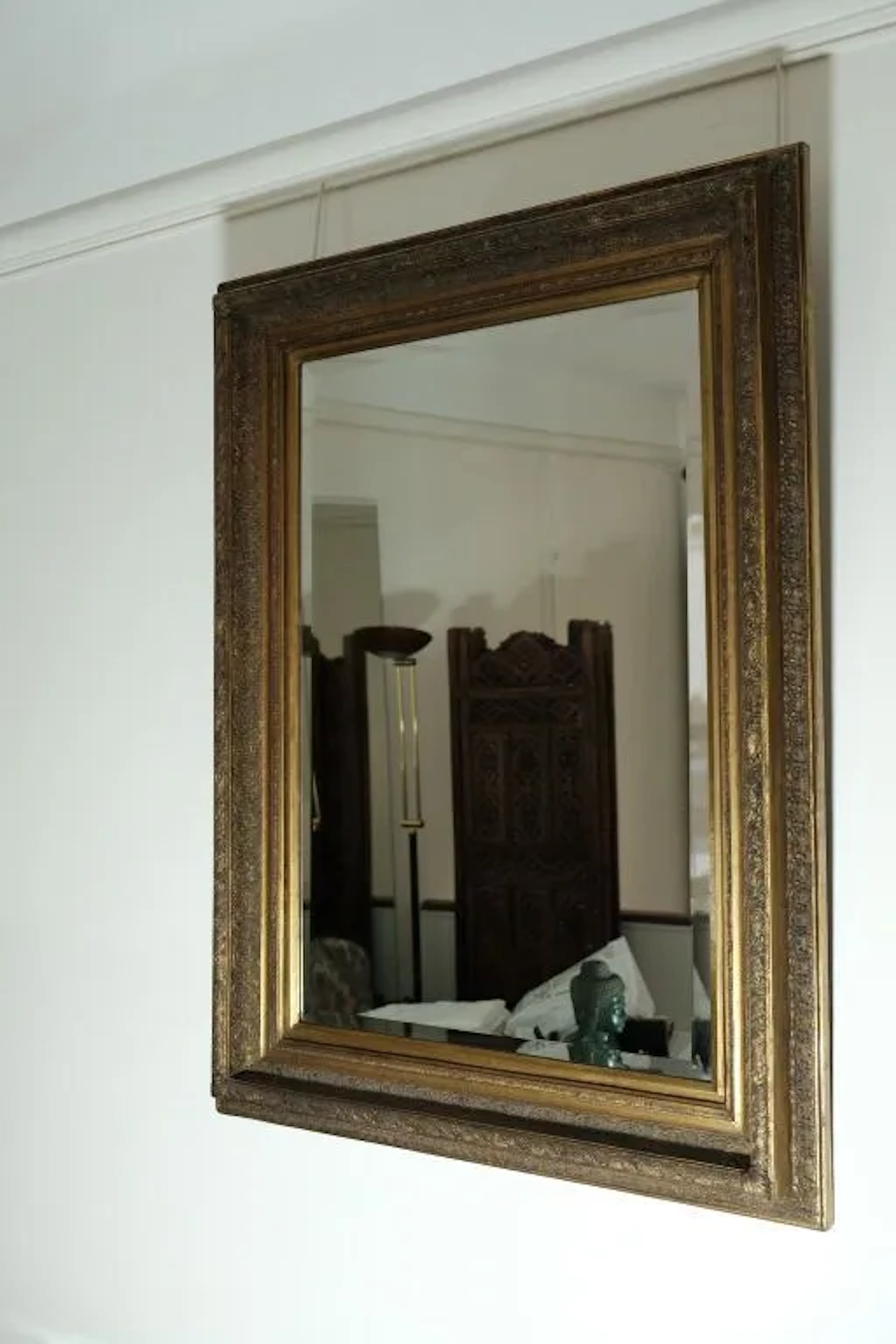 Large beveled mirror with a gilded stucco frame decorated with stylized