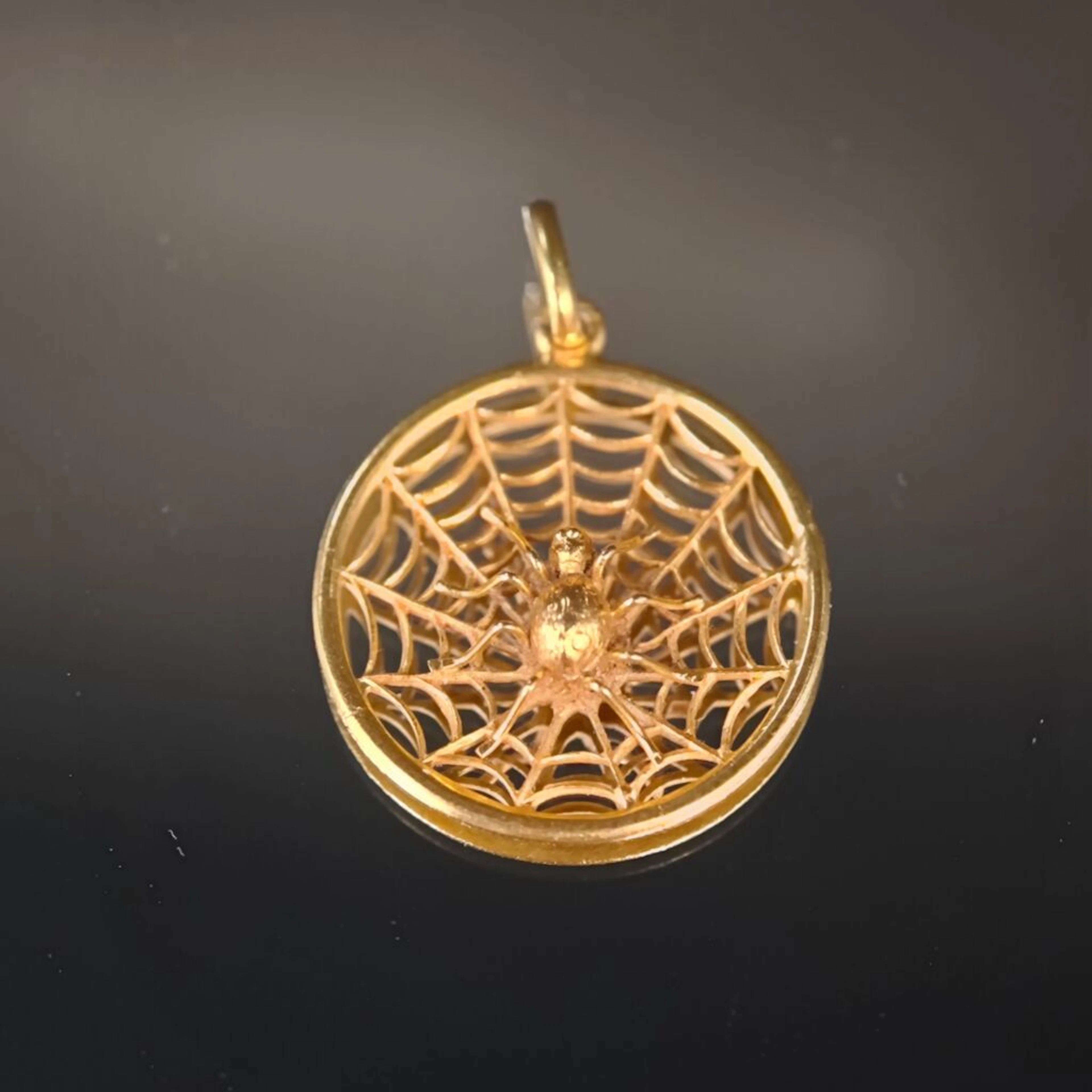 A re-drilled 750‰ yellow gold pendant featuring a spider in the center