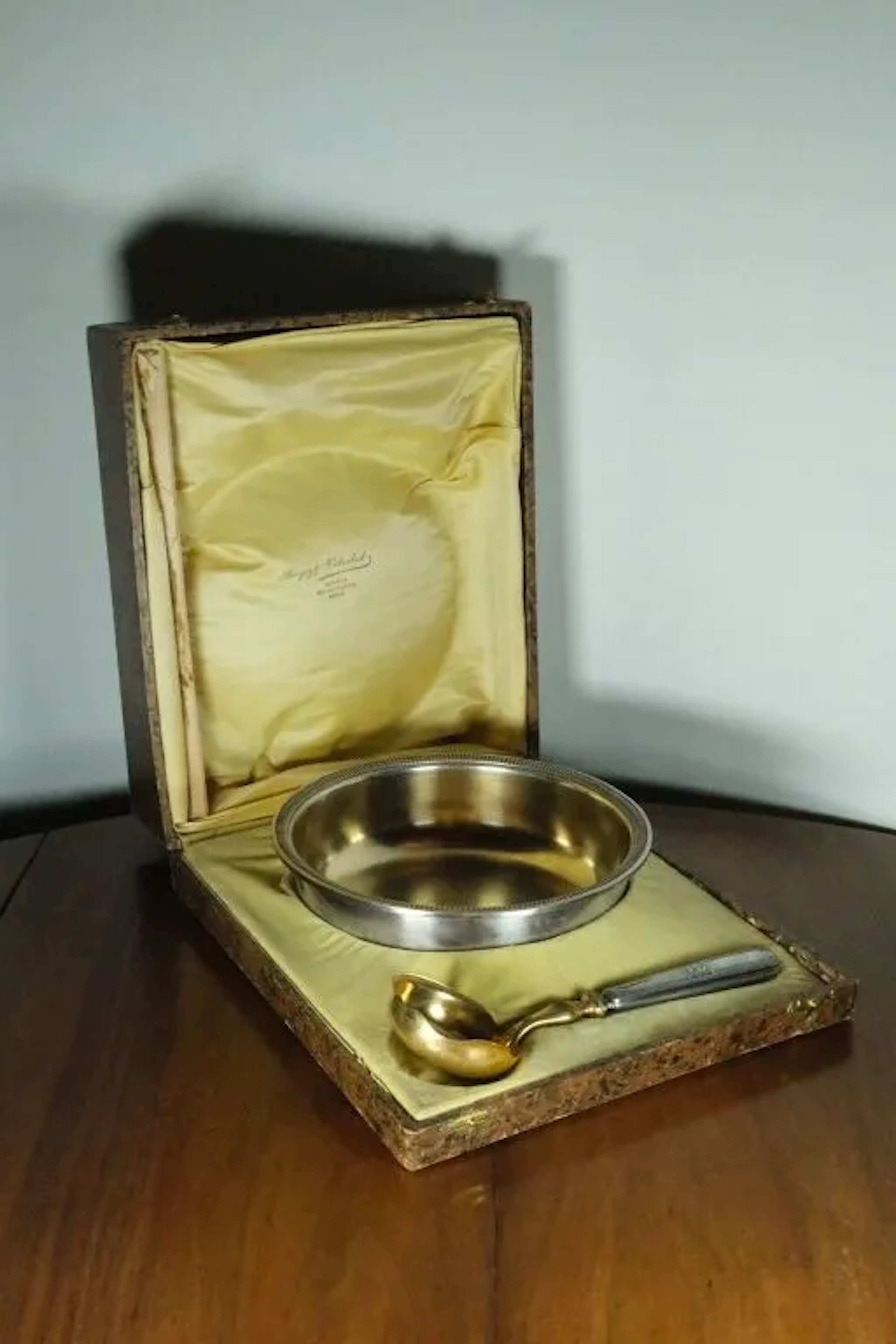 A deep, silver plated metal bowl with a fluted border, accompanied