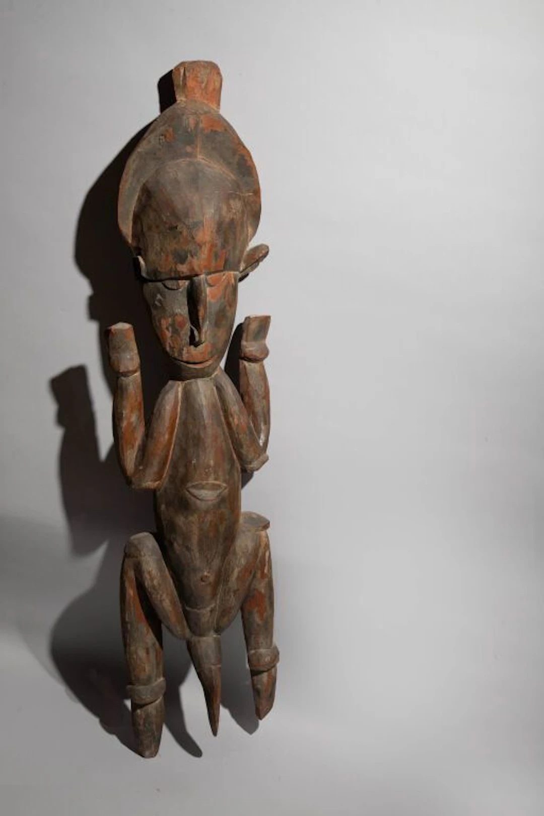 Male figure, legs bent, arms raised. Traces of original polychrome