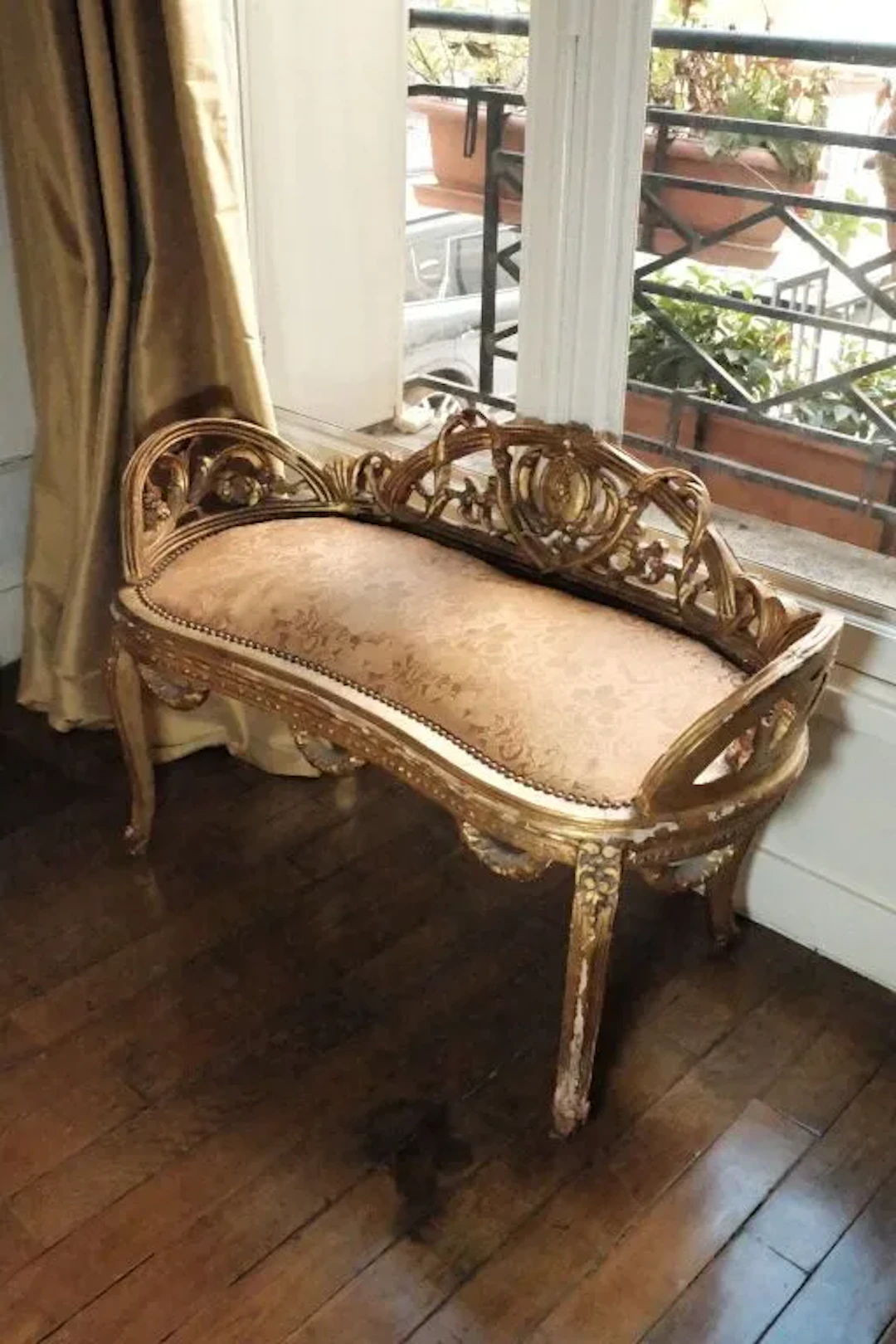 Small gilded and carved wooden bench with openwork foliage scrollwork.