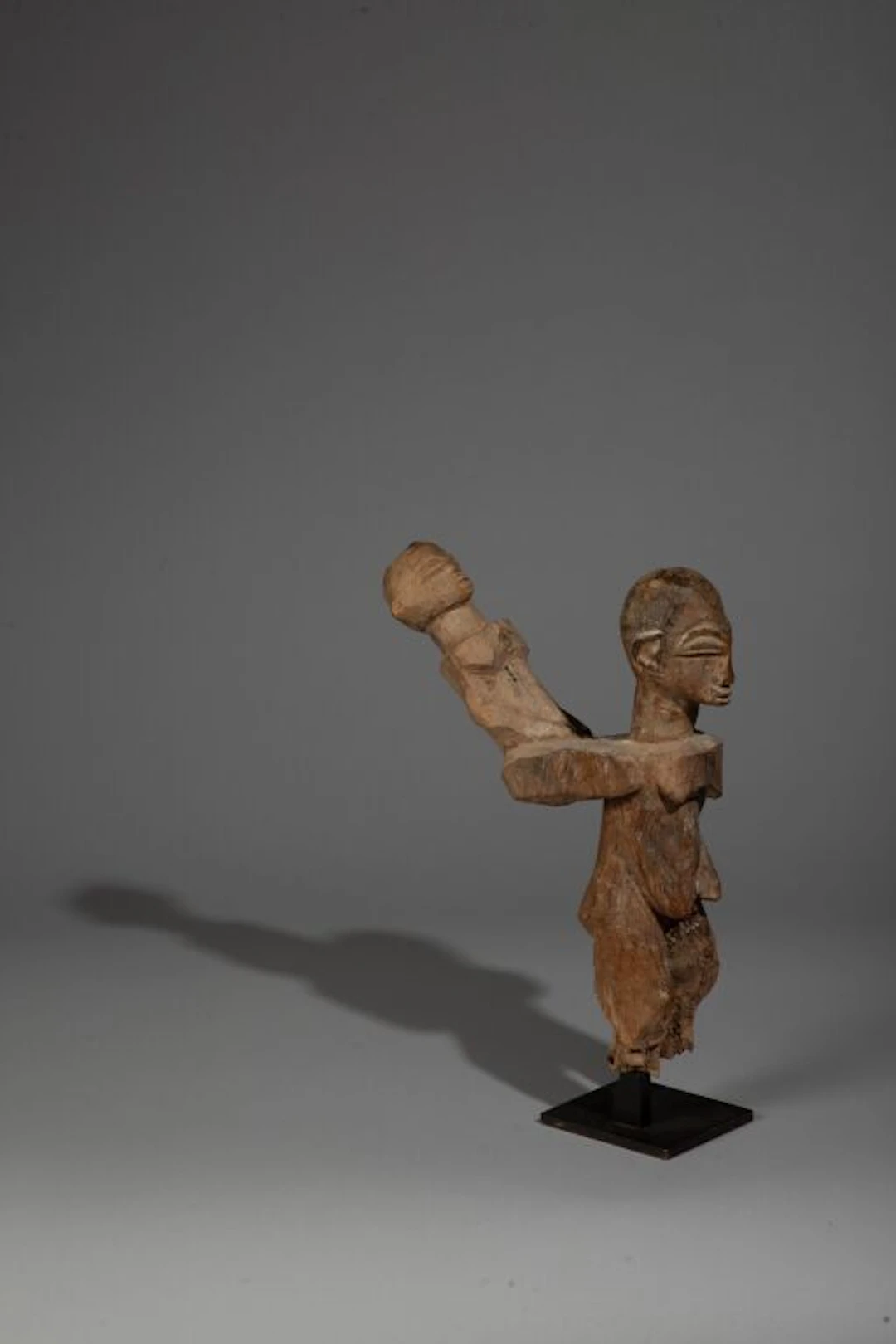 A mother carrying a child on her shoulders in a very recessed position.