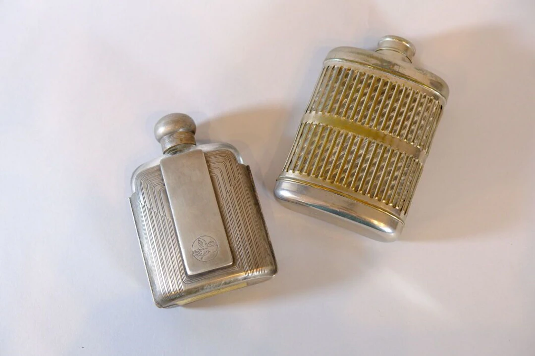 A set of two glass bottles with silver-plated metal frames, shaped