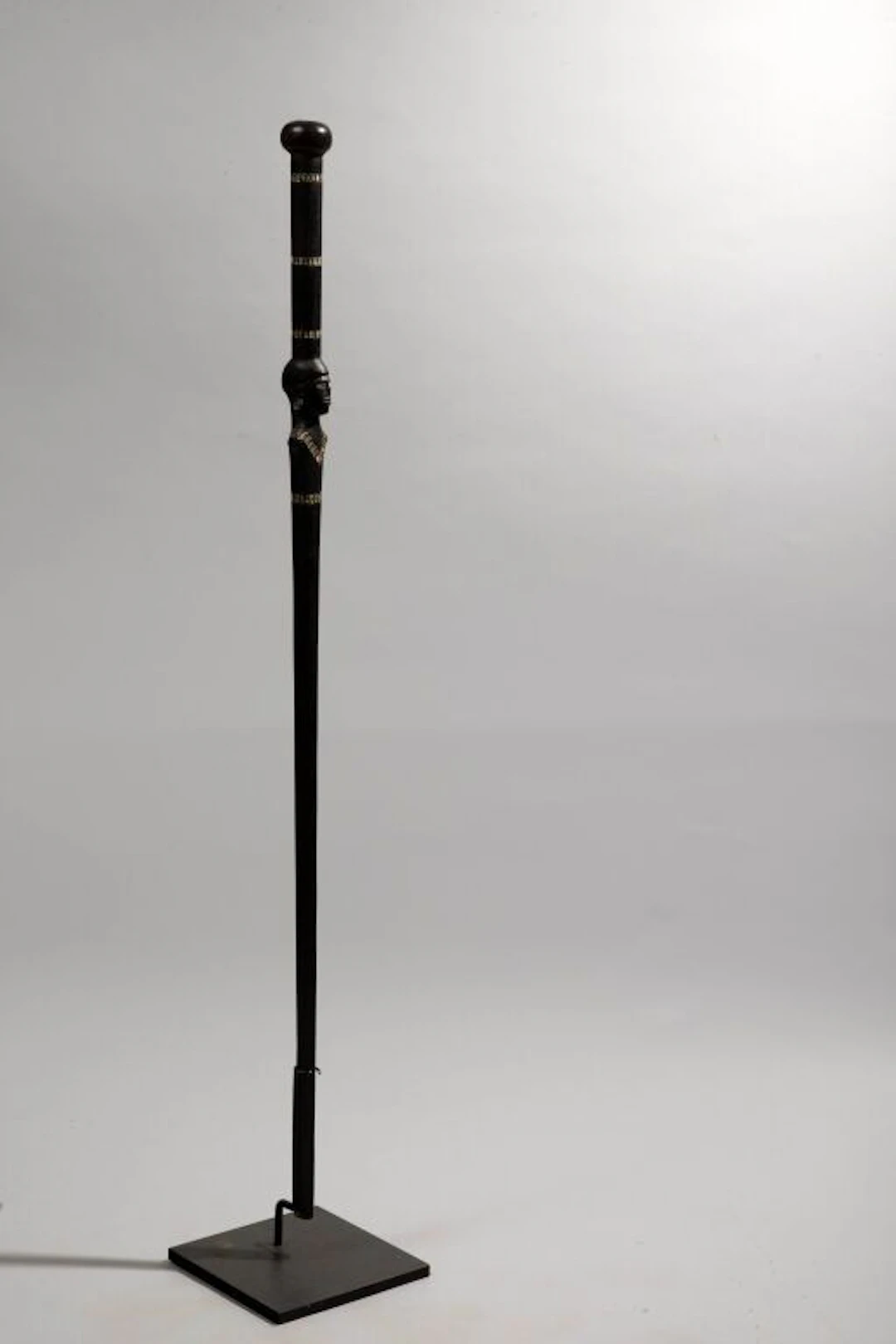 A walking stick decorated with a bust-style head at the handle, featuring