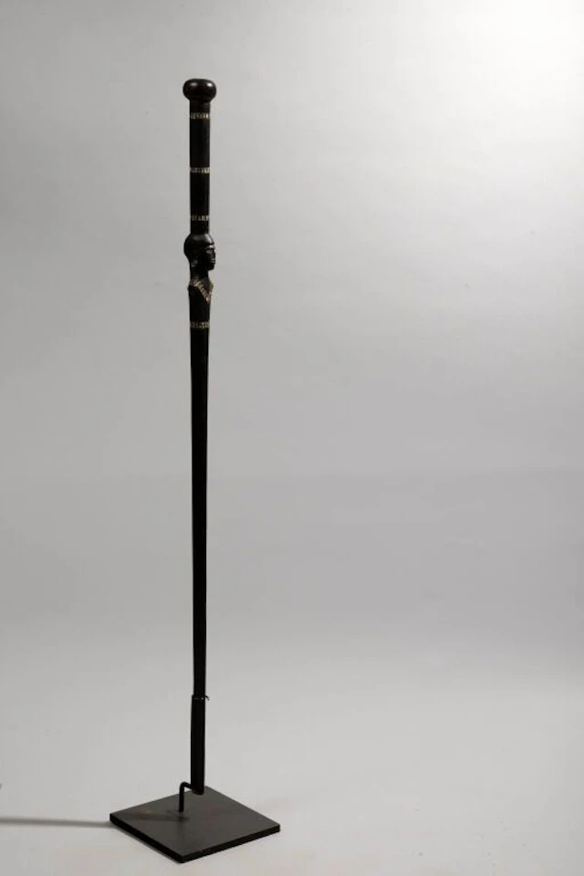 A walking stick decorated with a bust-style head at the handle, featuring