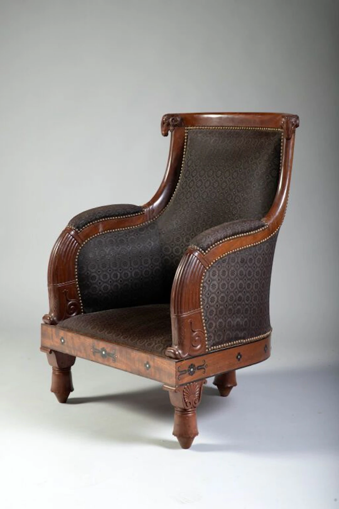 A rare low-seated bergère with a wraparound backrest, made of mahogany
