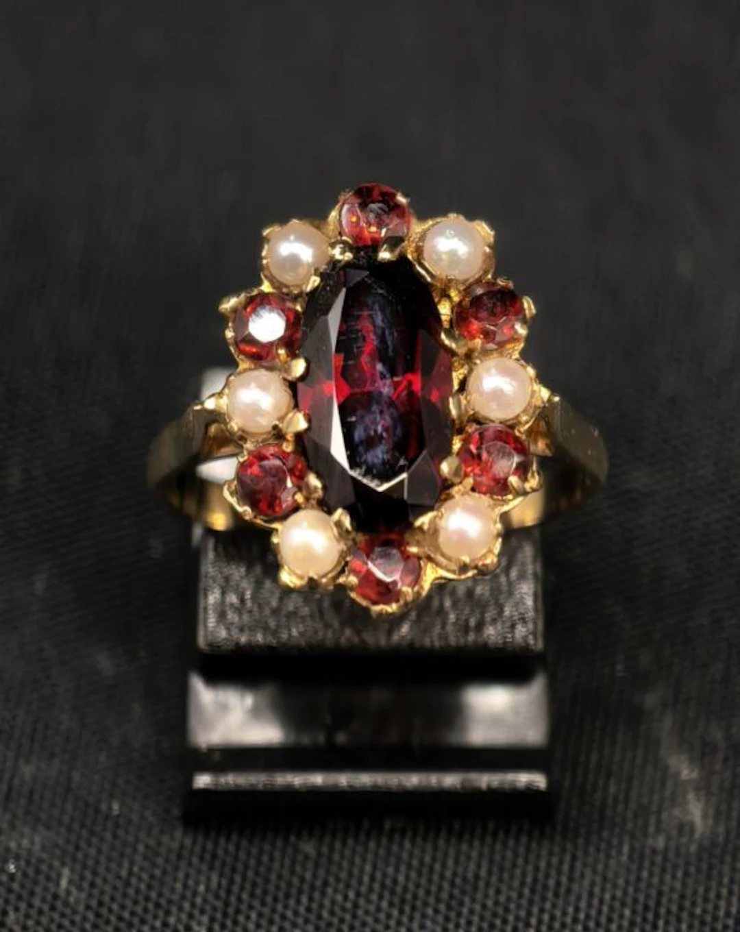 A 750‰ yellow gold ring set with an oval-shaped garnet surrounded