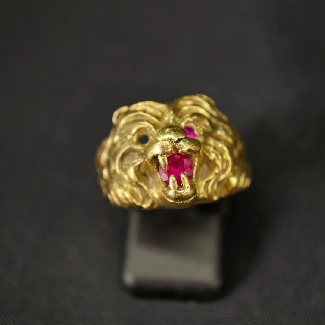 A 750‰ yellow gold ring featuring a lion's head holding an imitation