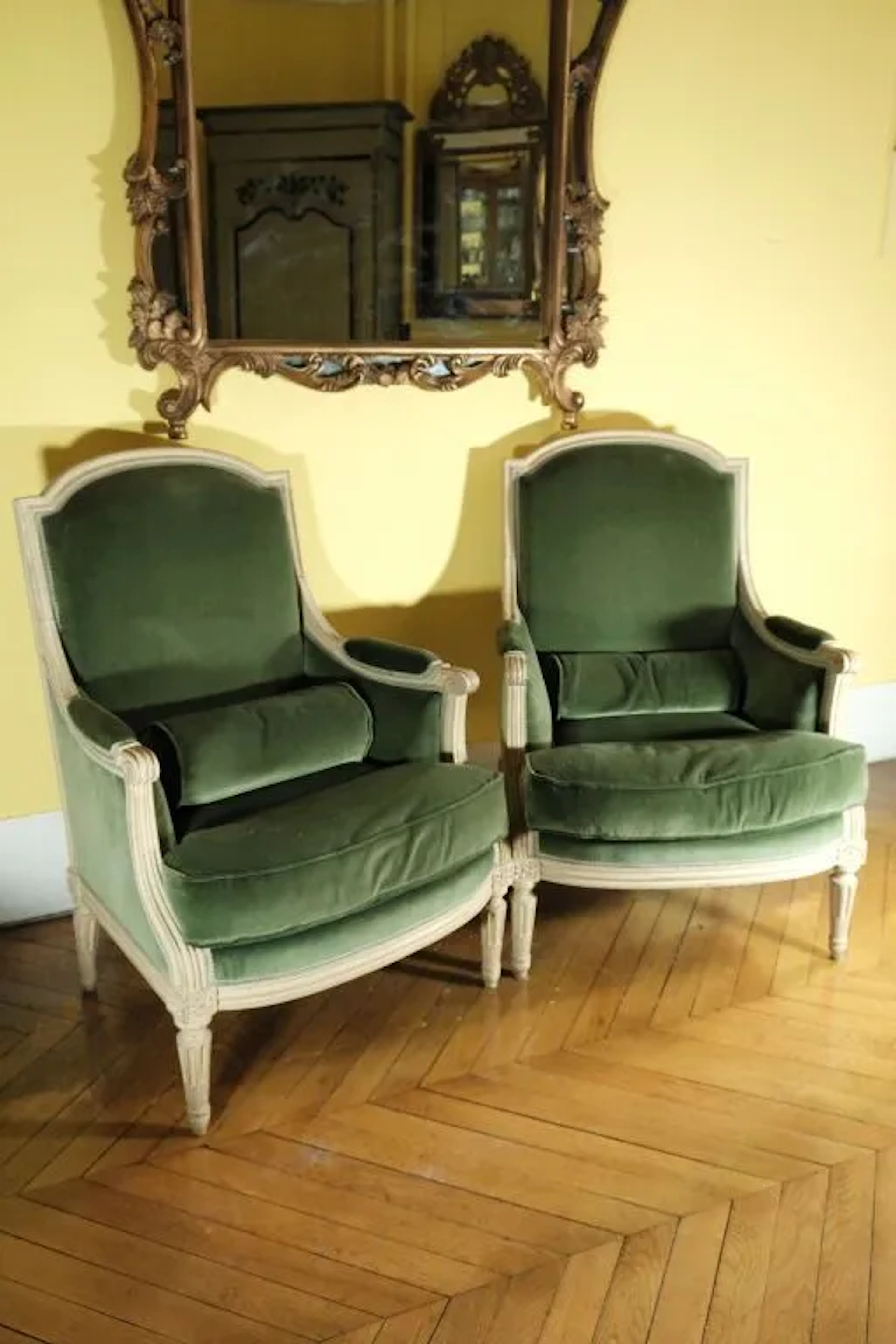 Pair of wooden bergère chairs with a cream-stained finish, featuring