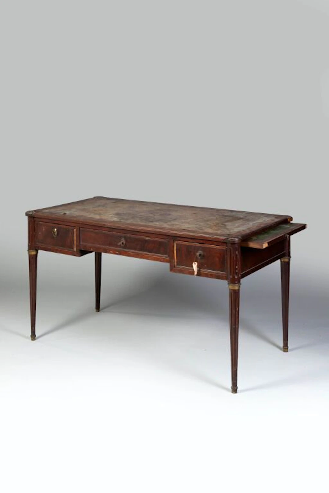 A flat mahogany-veneered desk with three drawers set in a band; the