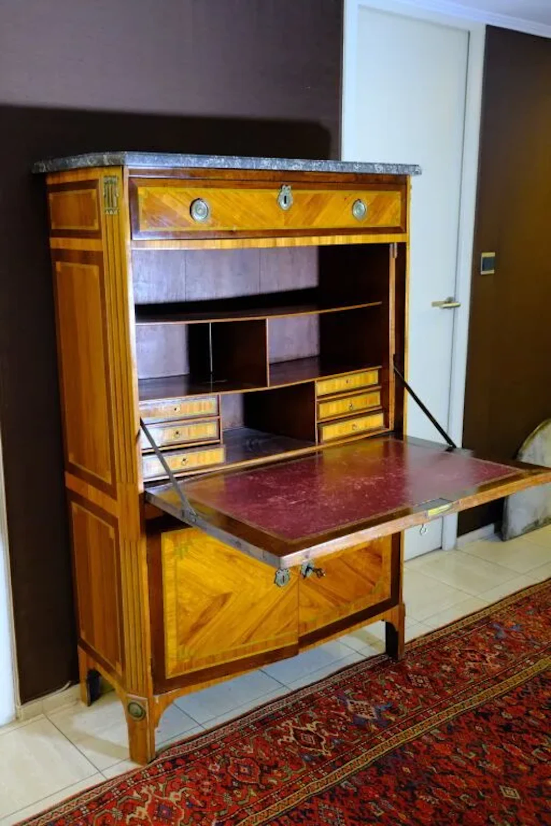 A veneered wooden secretary desk with a curly-grain marquetry design