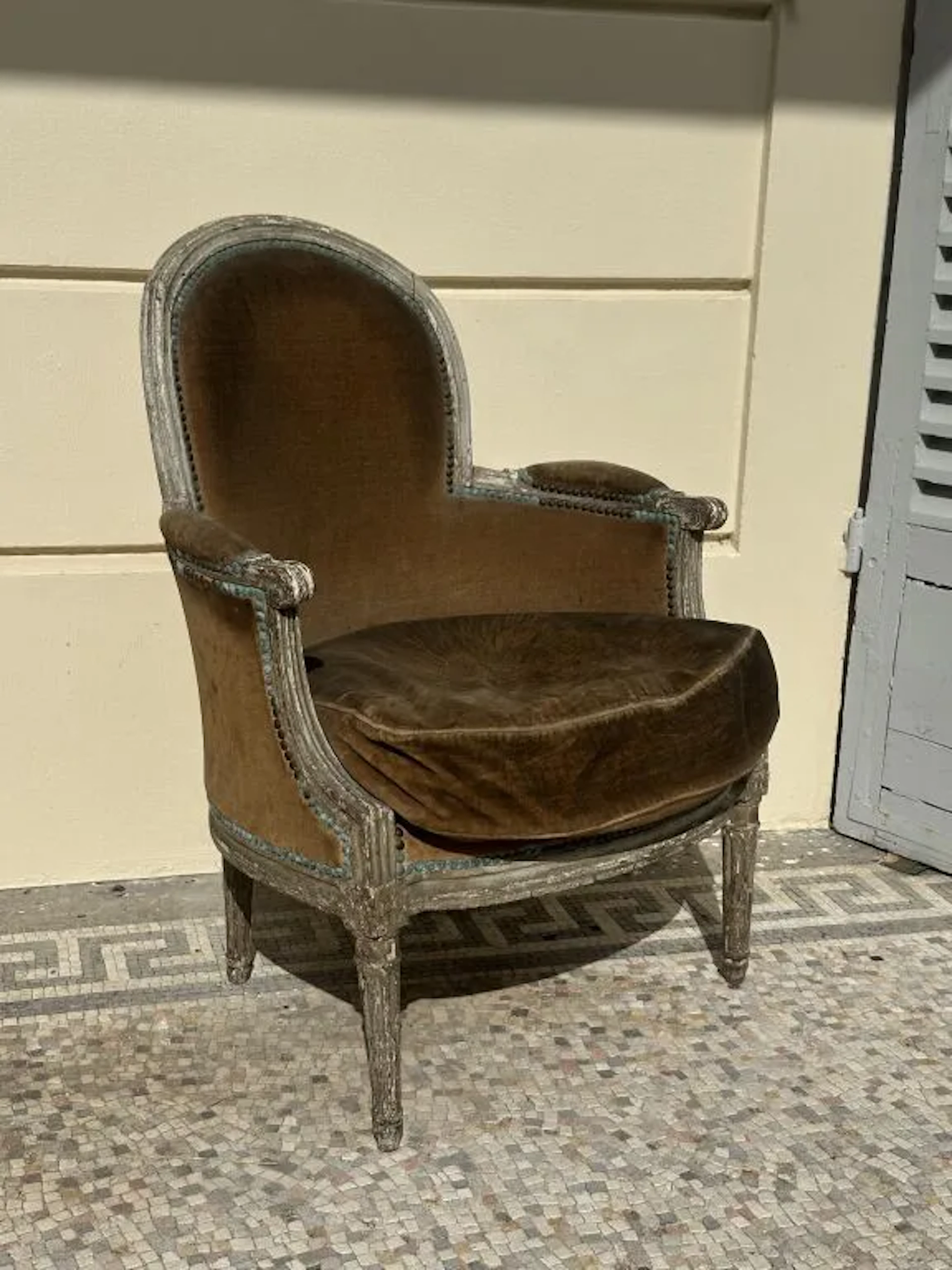 Molded and carved wooden bergère chair, refinished in cream. Tapered