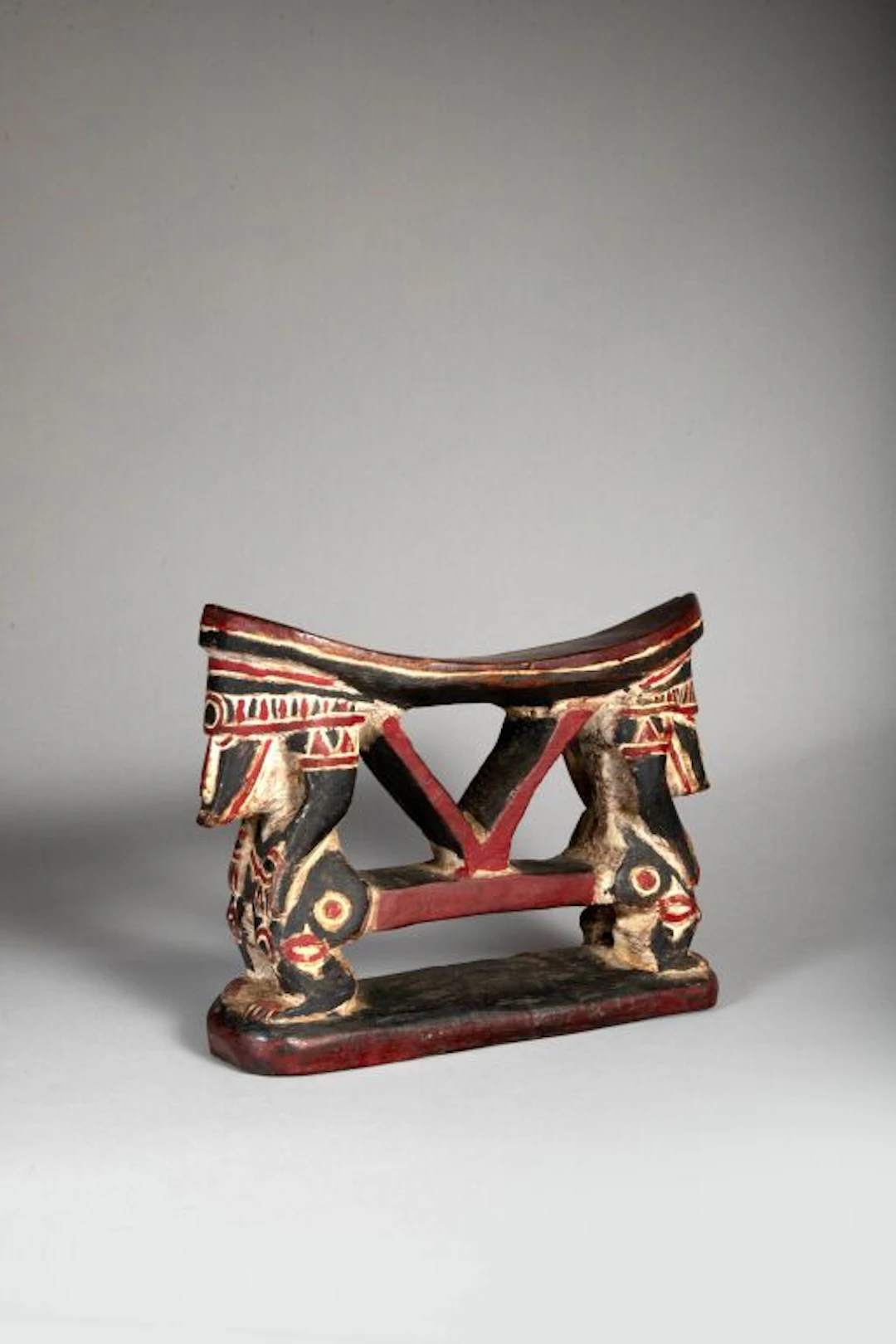 Neck rest featuring two opposing figures. Red and white polychrome