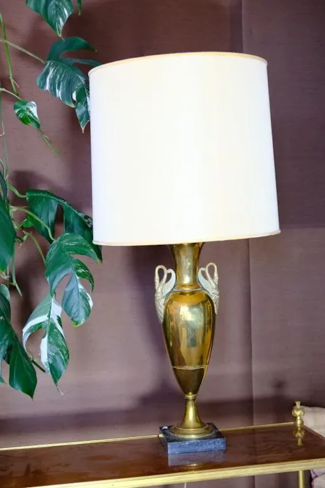 Copper urn-shaped living room lamp with swan-neck handles resting